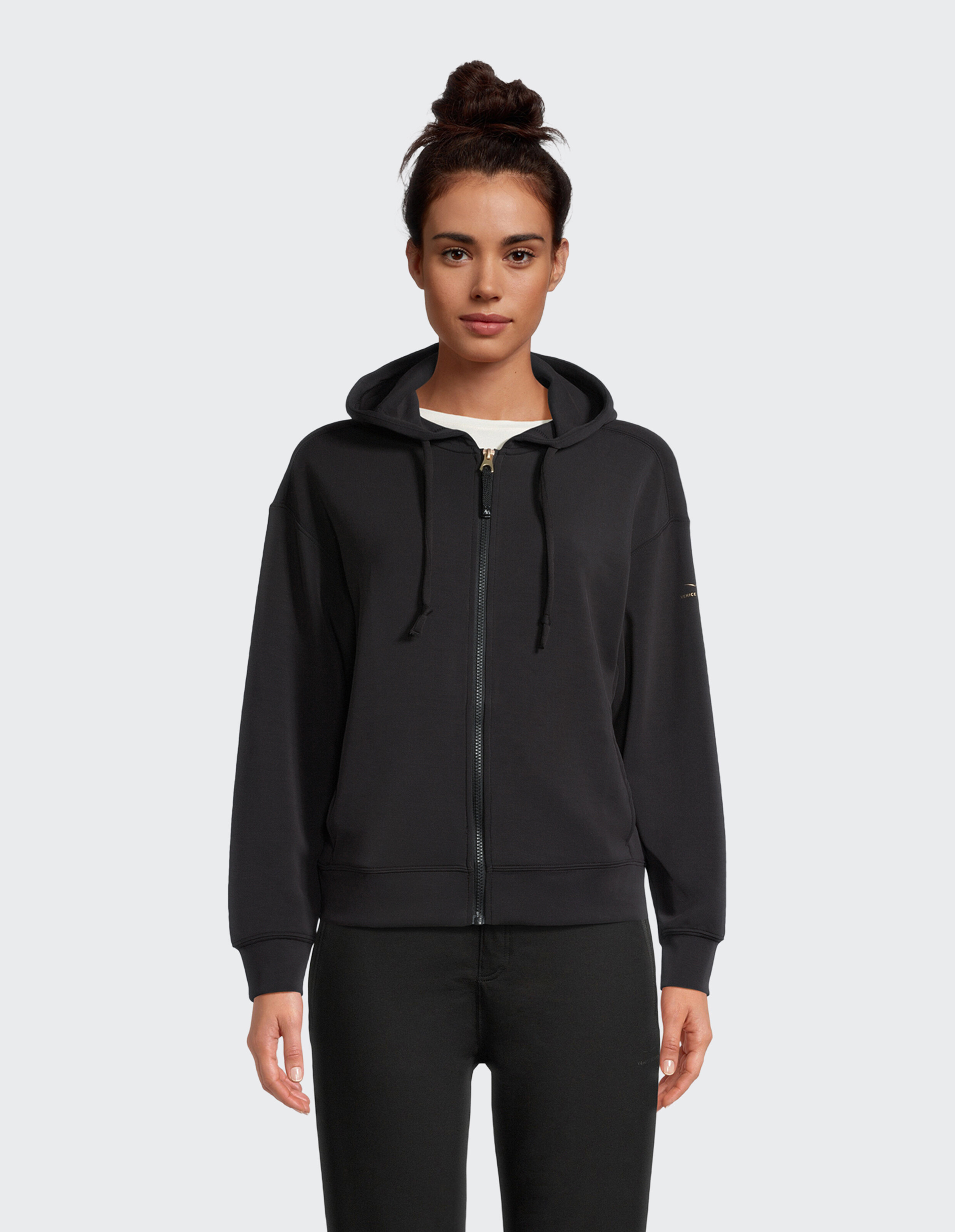 Frau trägt einen schwarzen Kapuzenpullover mit Reißverschluss, perfekt für gemütliche Freizeit-Loungewear.