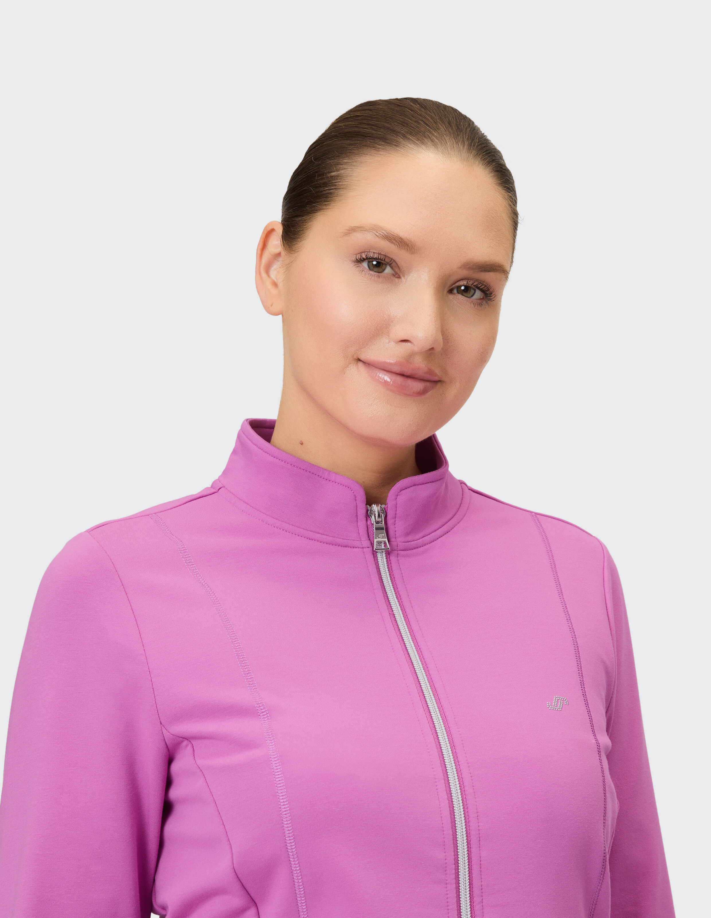 Frau in einer rosafarbenen Jacke mit Reißverschluss, die einen gemütlichen und stilvollen Freizeitlook präsentiert.