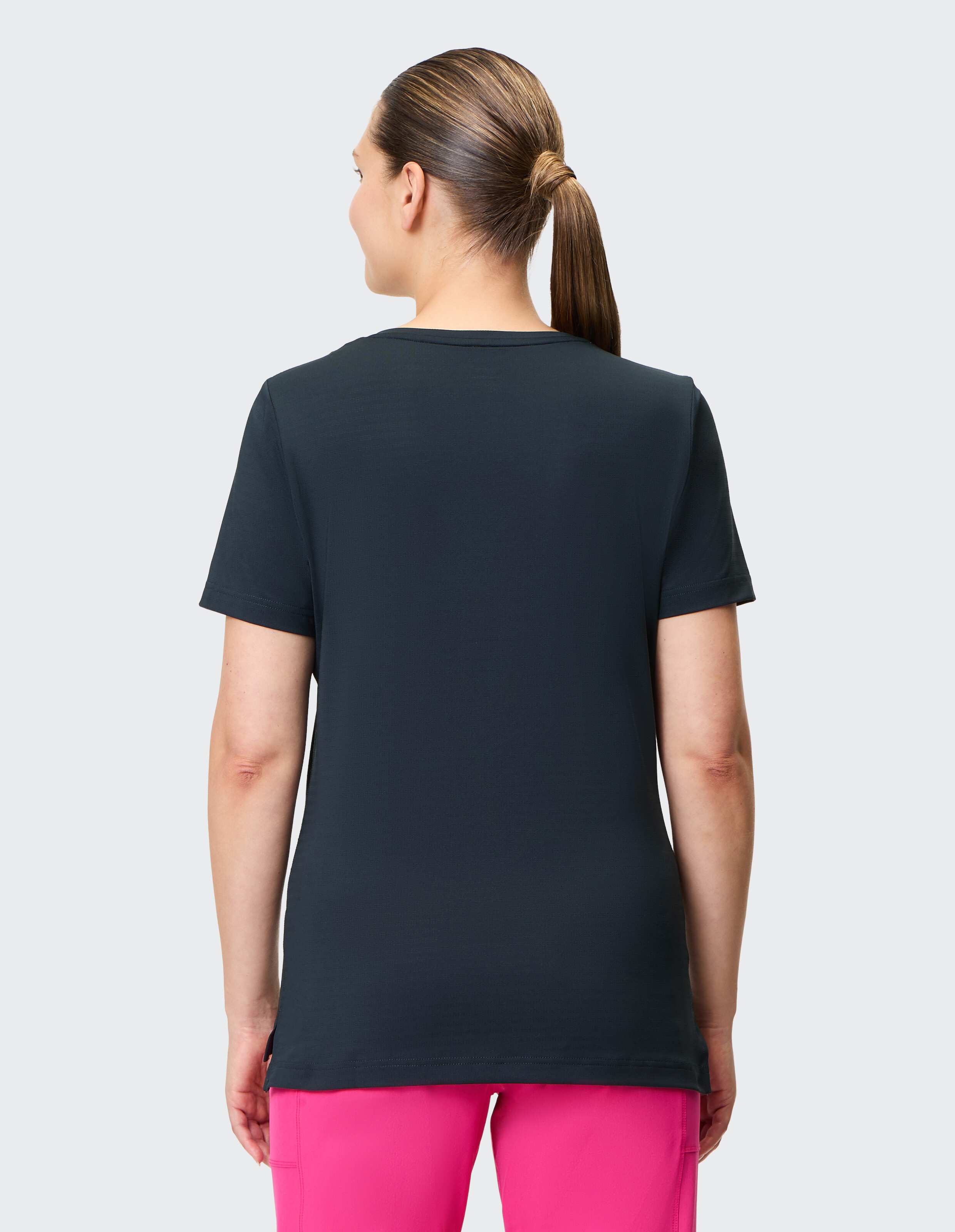 Rückansicht einer Frau in einem dunklen T-Shirt und einer rosa Hose, die einen lässigen Stil zur Schau stellt.