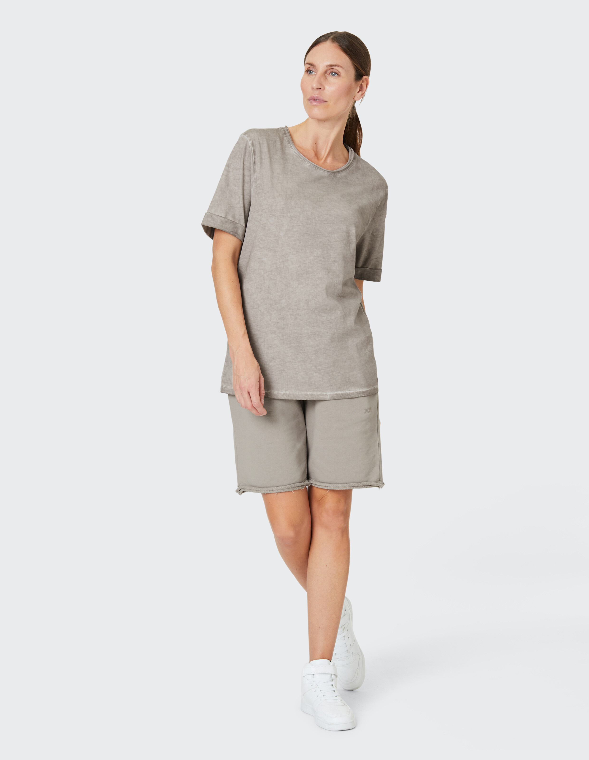 Frau in einem entspannten grauen T-Shirt und passenden Shorts, gestylt für lässigen Komfort.