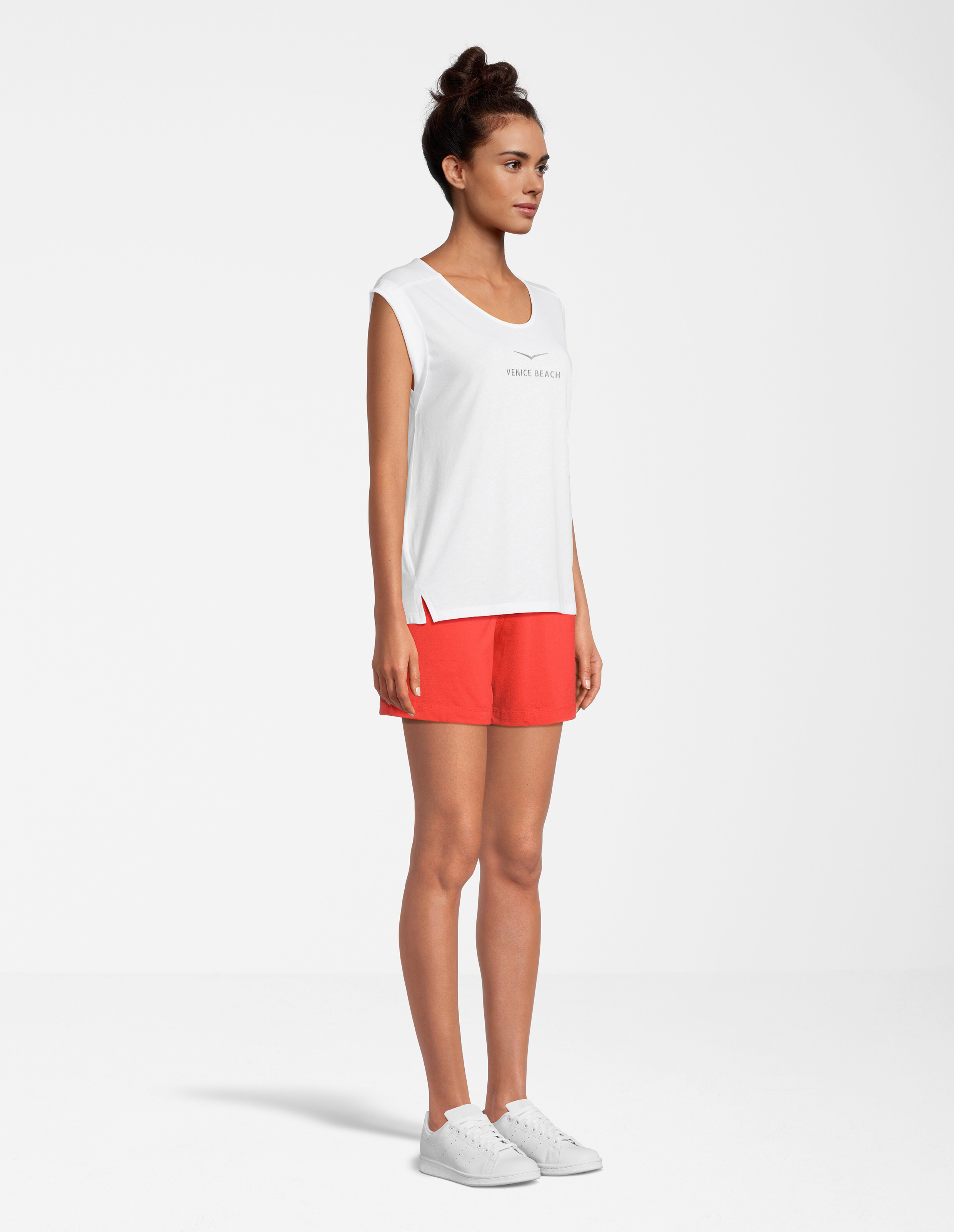 Das Model trägt ein weißes Tanktop von Venice Beach und rote Shorts, perfekt für Freizeitausflüge.