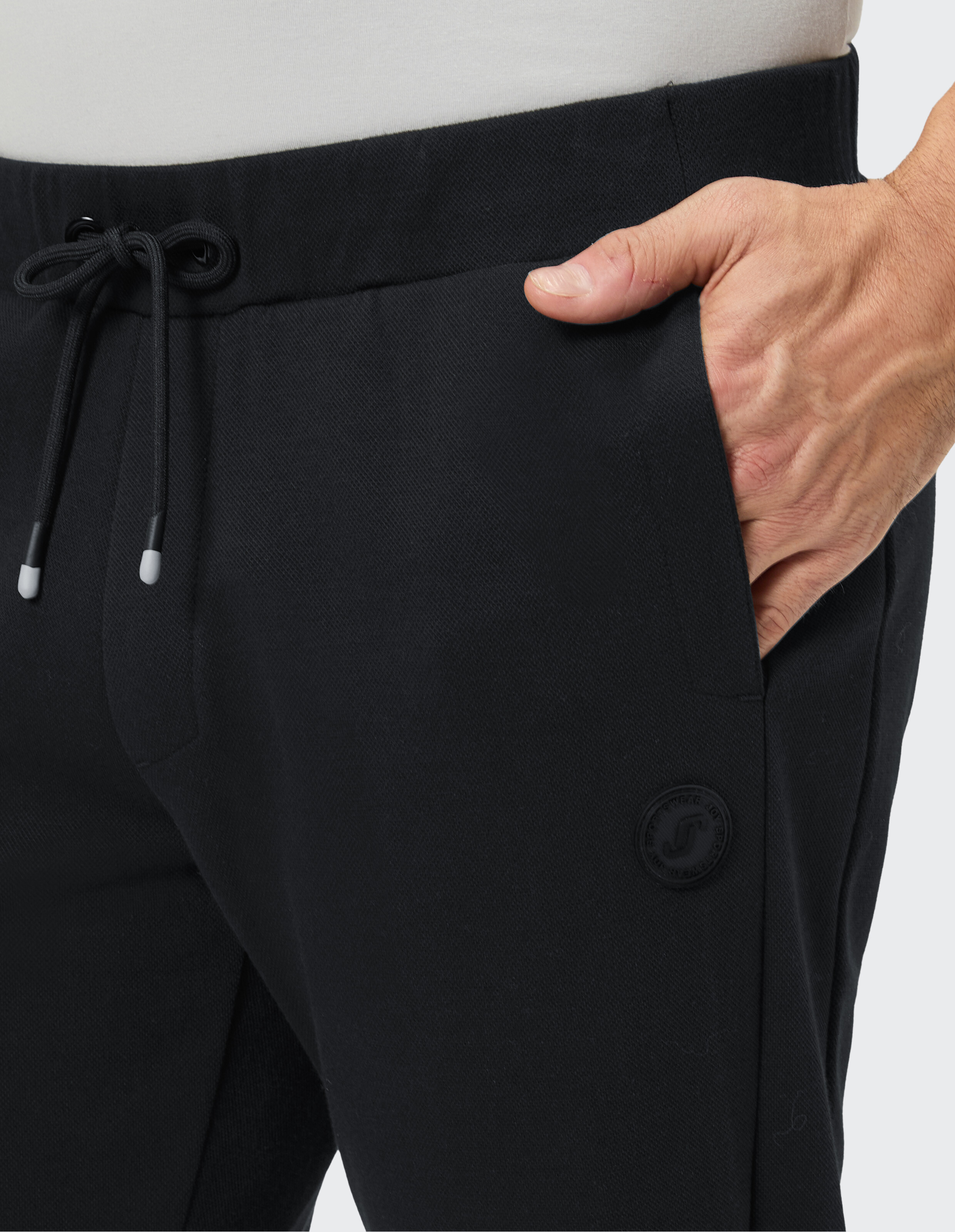 Nahaufnahme einer schwarzen Freizeithose mit Kordelzug und Seitentaschendetail.
