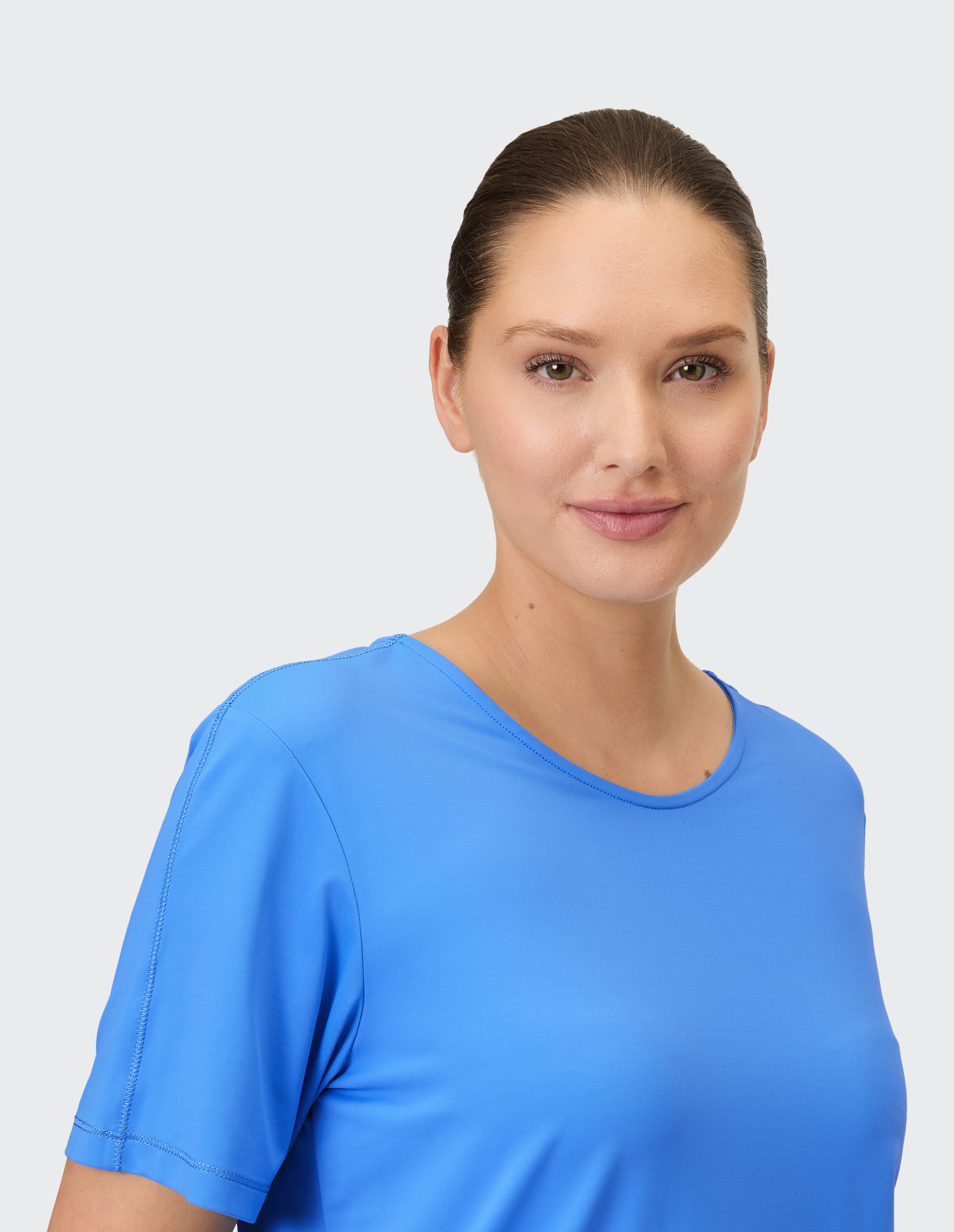 Nahaufnahme einer Frau, die ein blaues, kurzärmliges Freizeitoberteil trägt, das Komfort und Stil zur Schau stellt.
