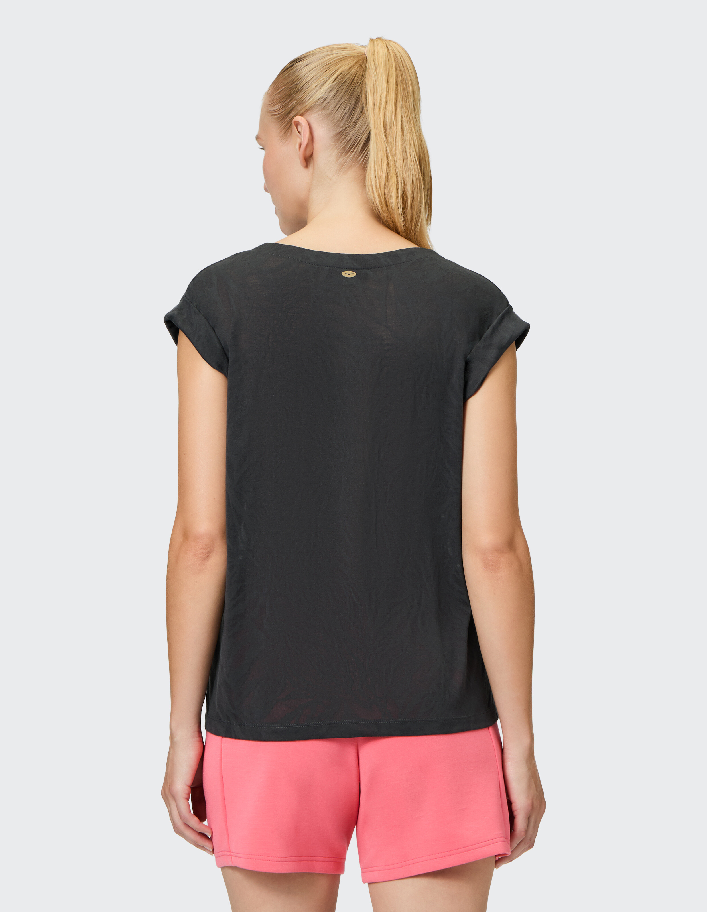 Rückansicht einer Frau in einem schwarzen Kurzarm-Top und rosa Shorts.