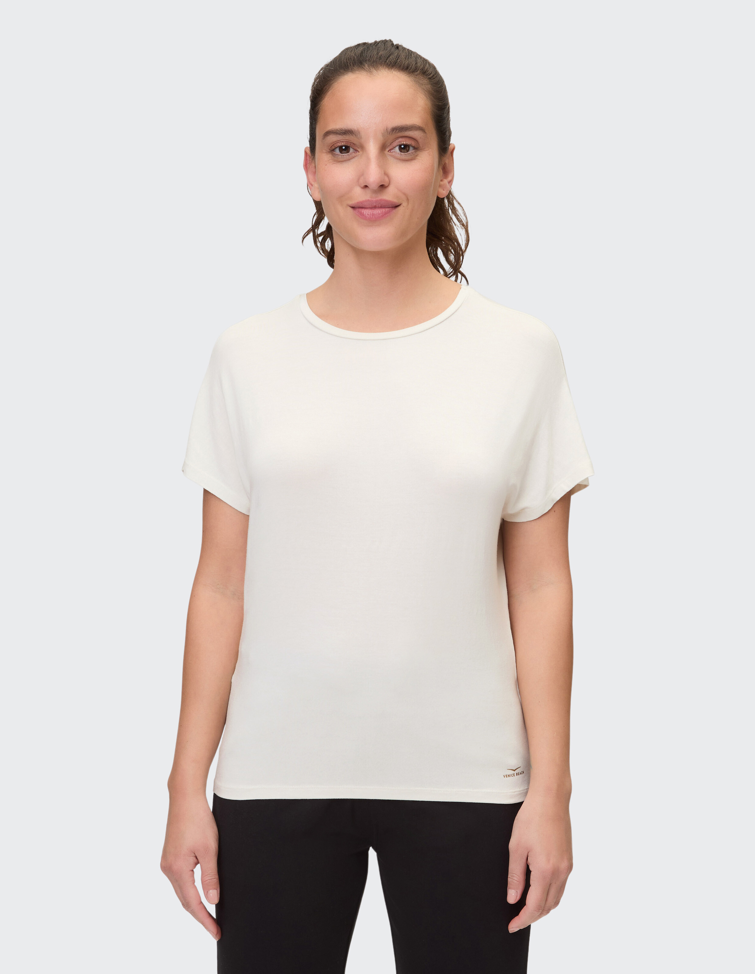 Frau trägt ein gemütliches cremefarbenes Freizeit-T-Shirt mit kurzen Ärmeln.
