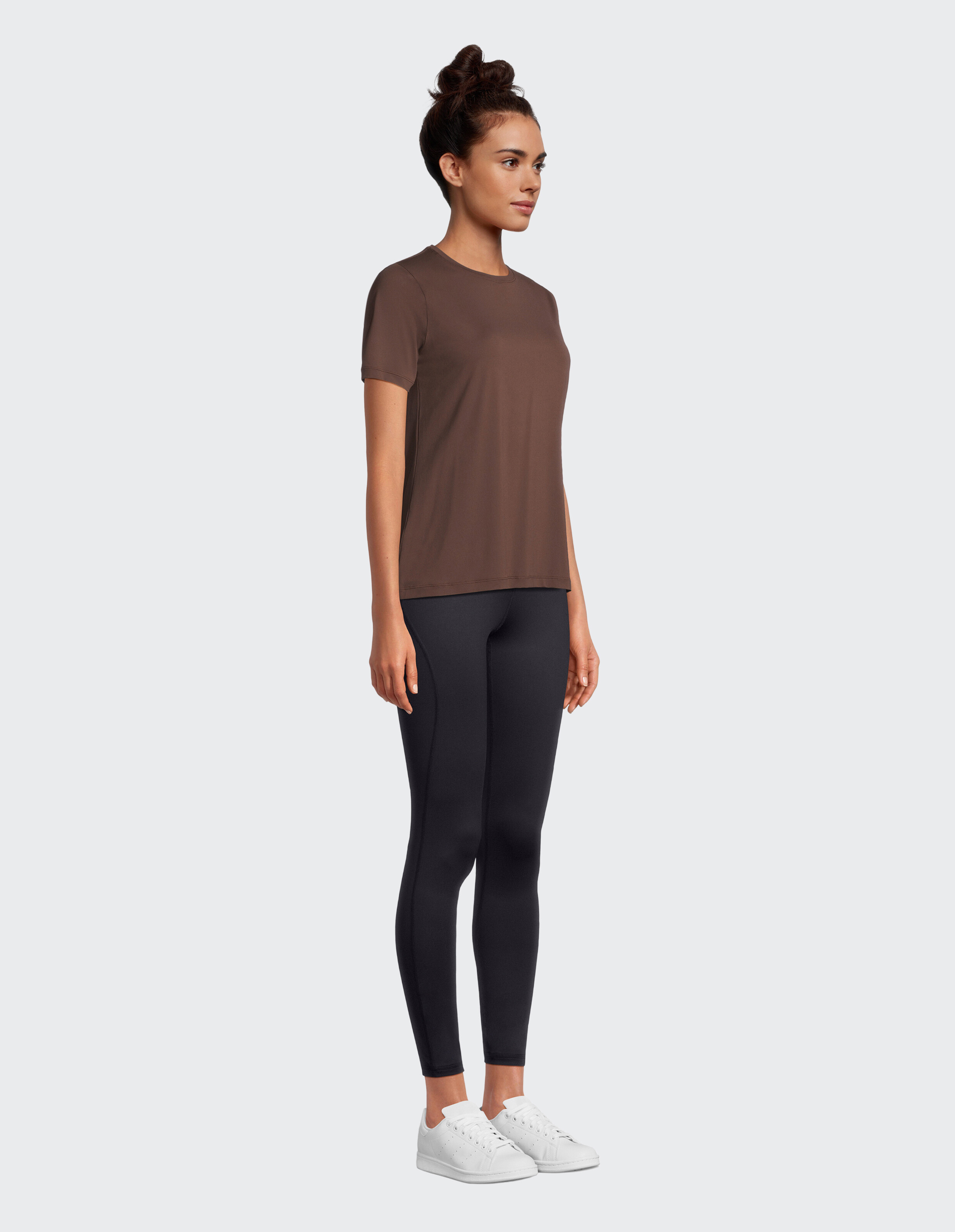 Frau trägt ein braunes Venice Beach Sia-Kurzarmhemd und schwarze Leggings.