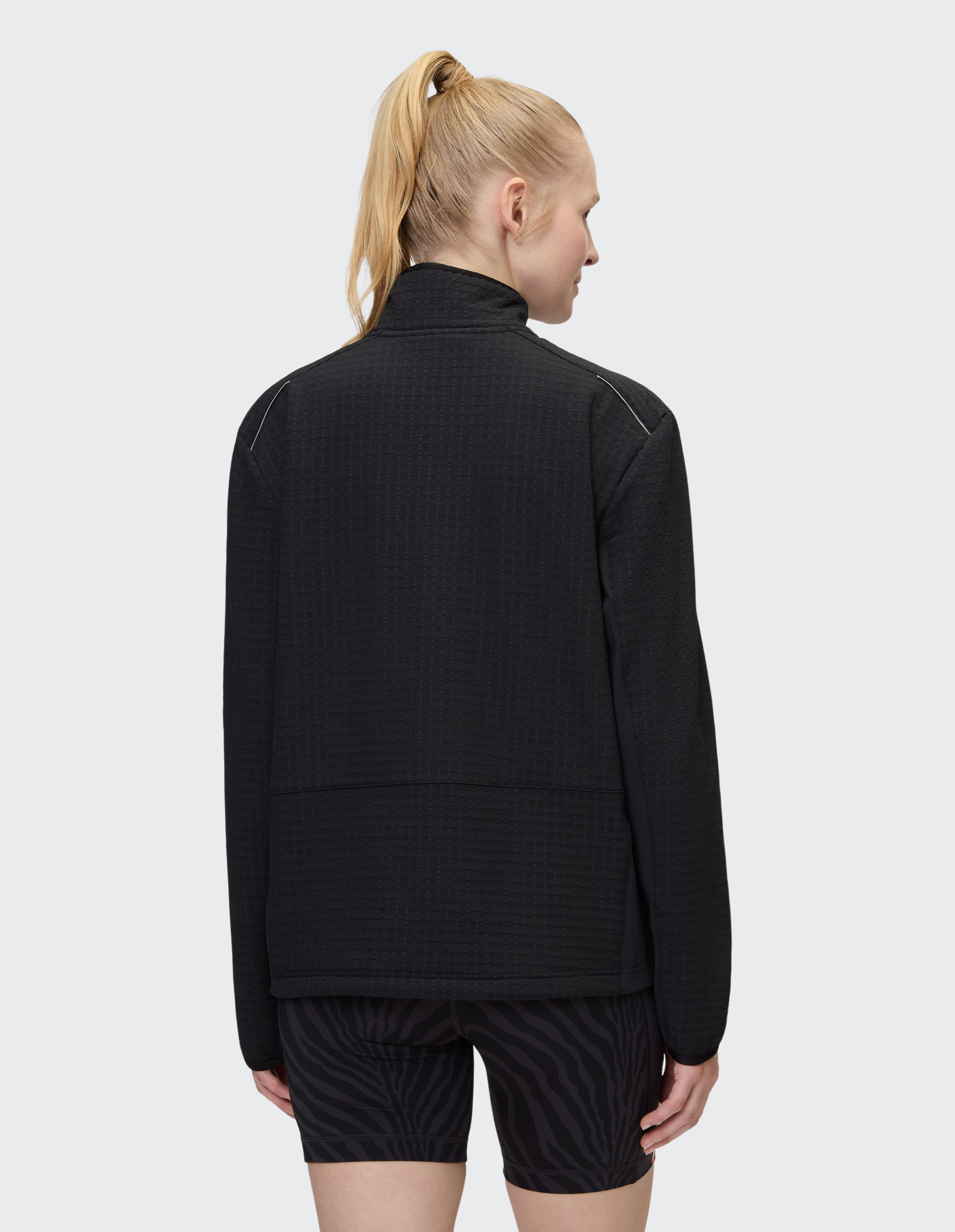 Frau trägt eine schwarze, strukturierte, lässige Jacke mit Reißverschluss, perfekt für gemütliche Loungewear.