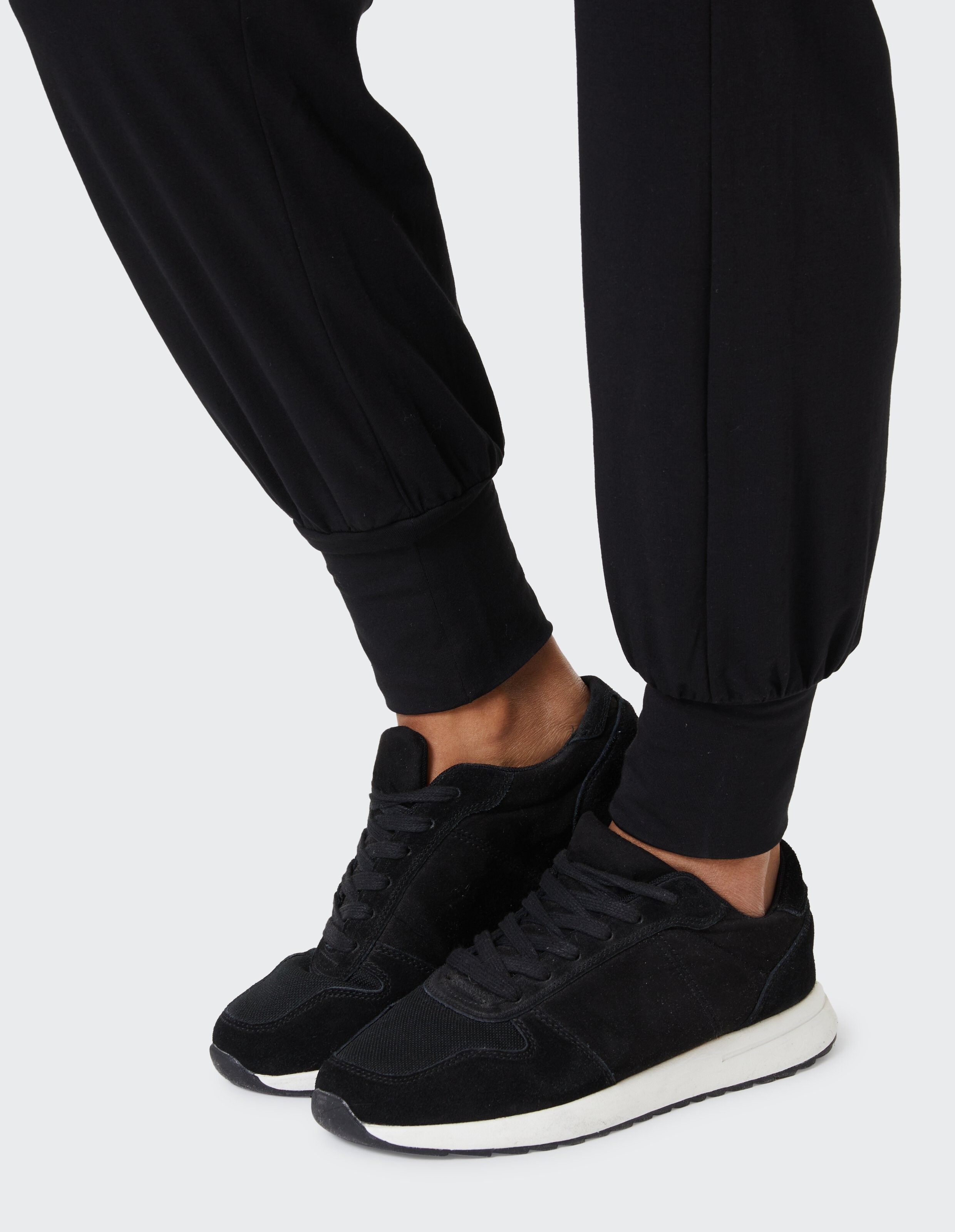 Nahaufnahme von schwarzen Freizeit-Sneakern gepaart mit einer schwarzen Jogginghose.