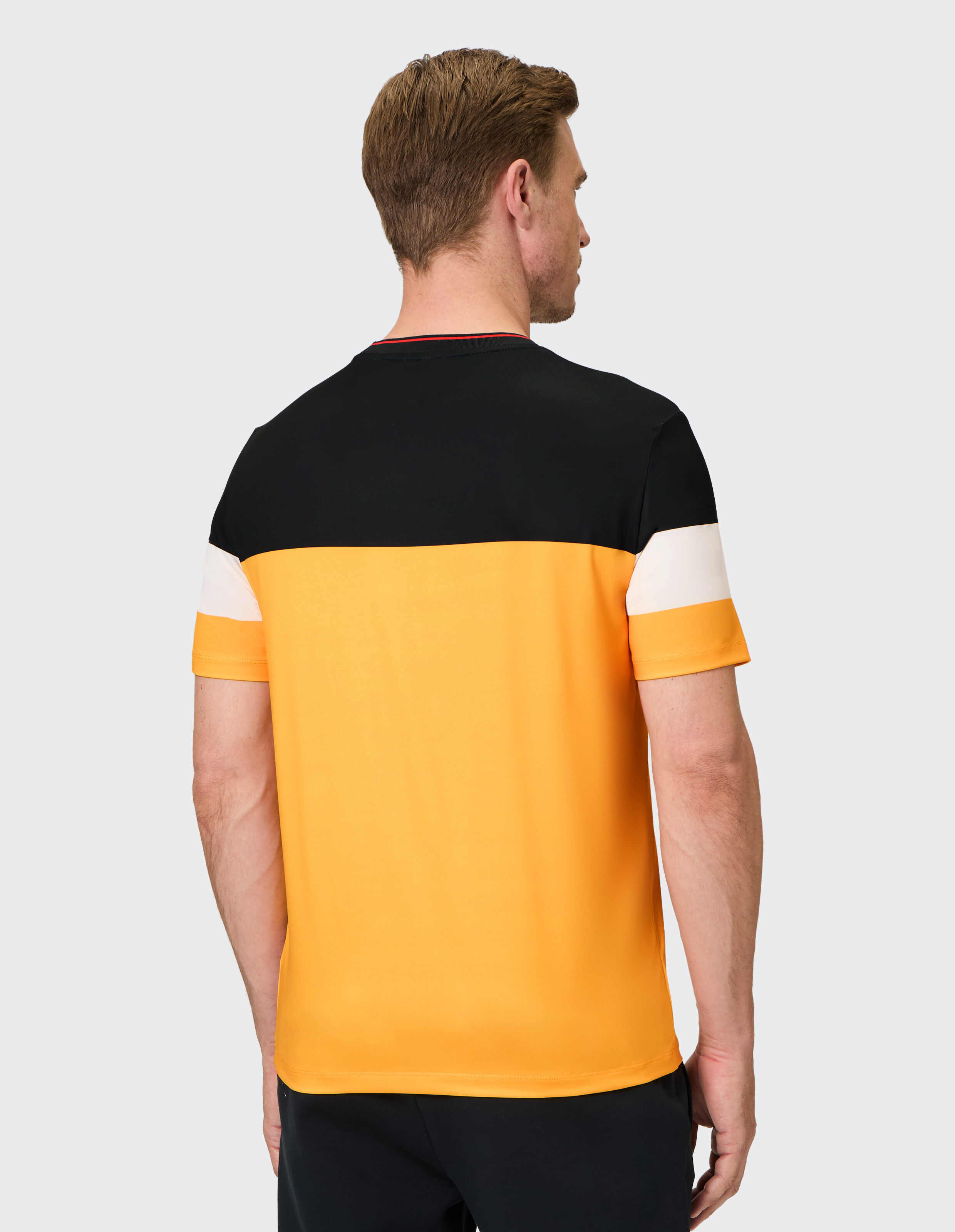 Mann trägt ein lässiges Farbblock-T-Shirt in Schwarz, Weiß und Gelb.