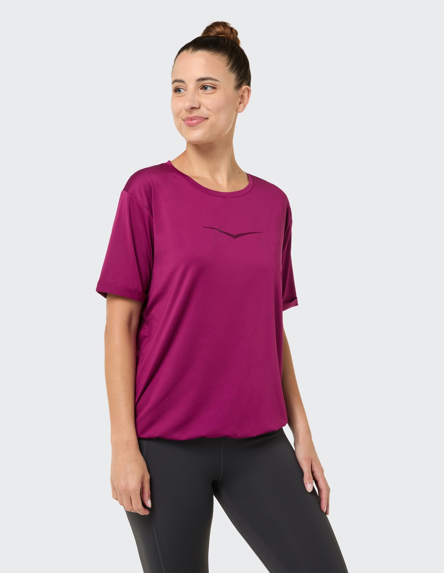 Frau trägt ein locker sitzendes magentafarbenes T-Shirt, perfekt für Freizeitausflüge.
