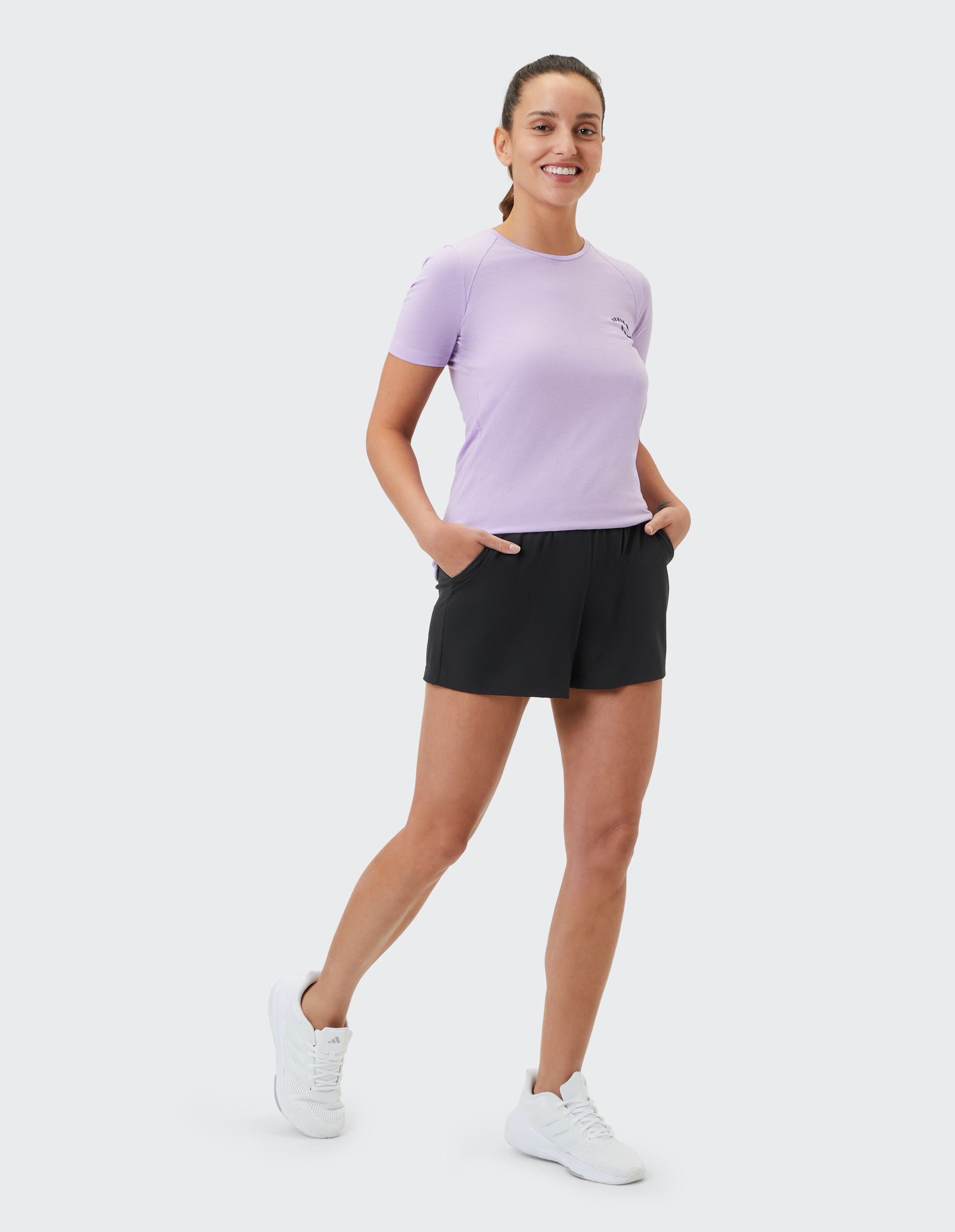 Frau in einem lavendelfarbenen T-Shirt und schwarzen Shorts, perfekt für Freizeitausflüge.