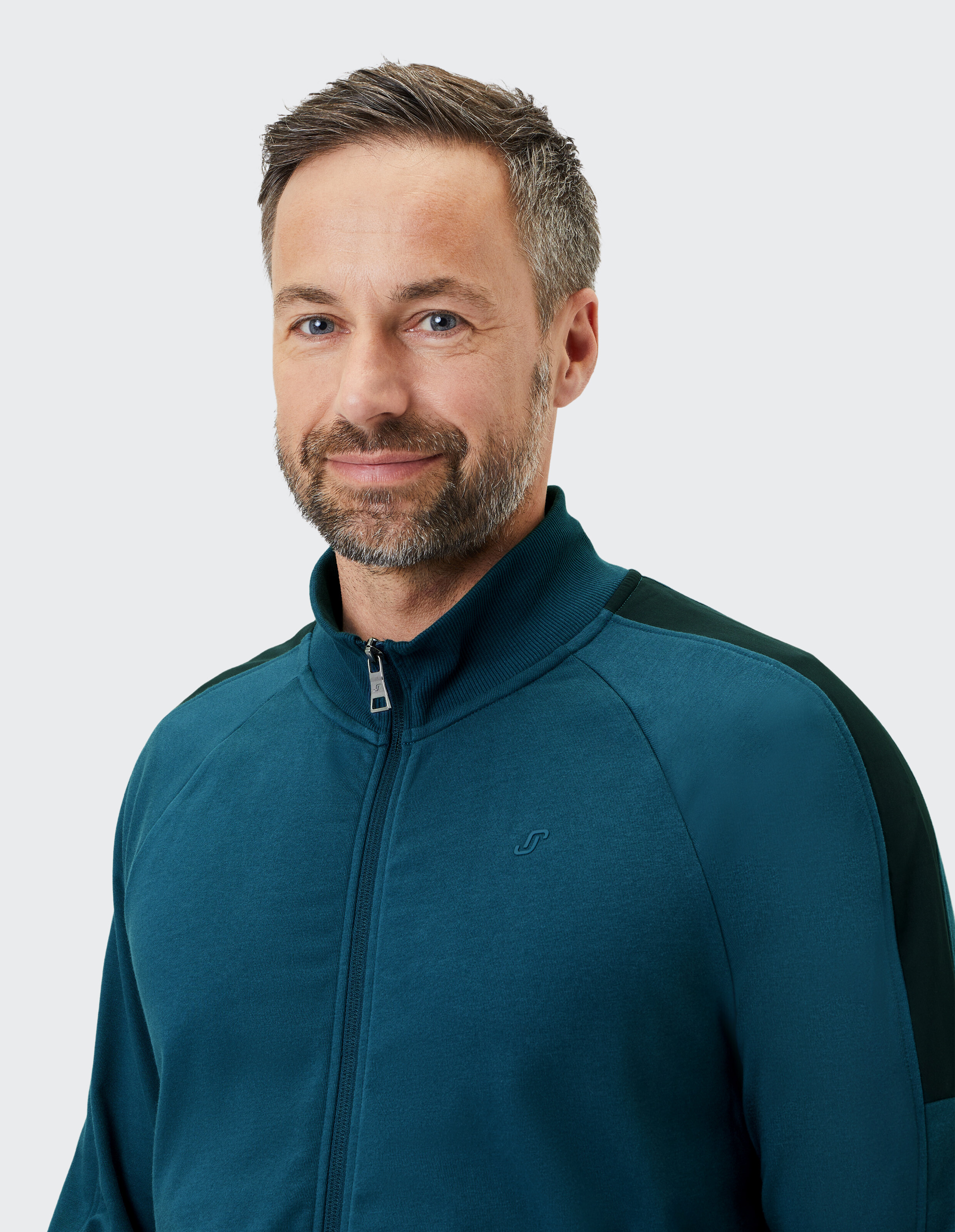 Blauer Trainingsanzug mit Reißverschlussjacke und langen Ärmeln, Hose mit elastischem Bund, schwarze Akzente an Schultern und Seiten.