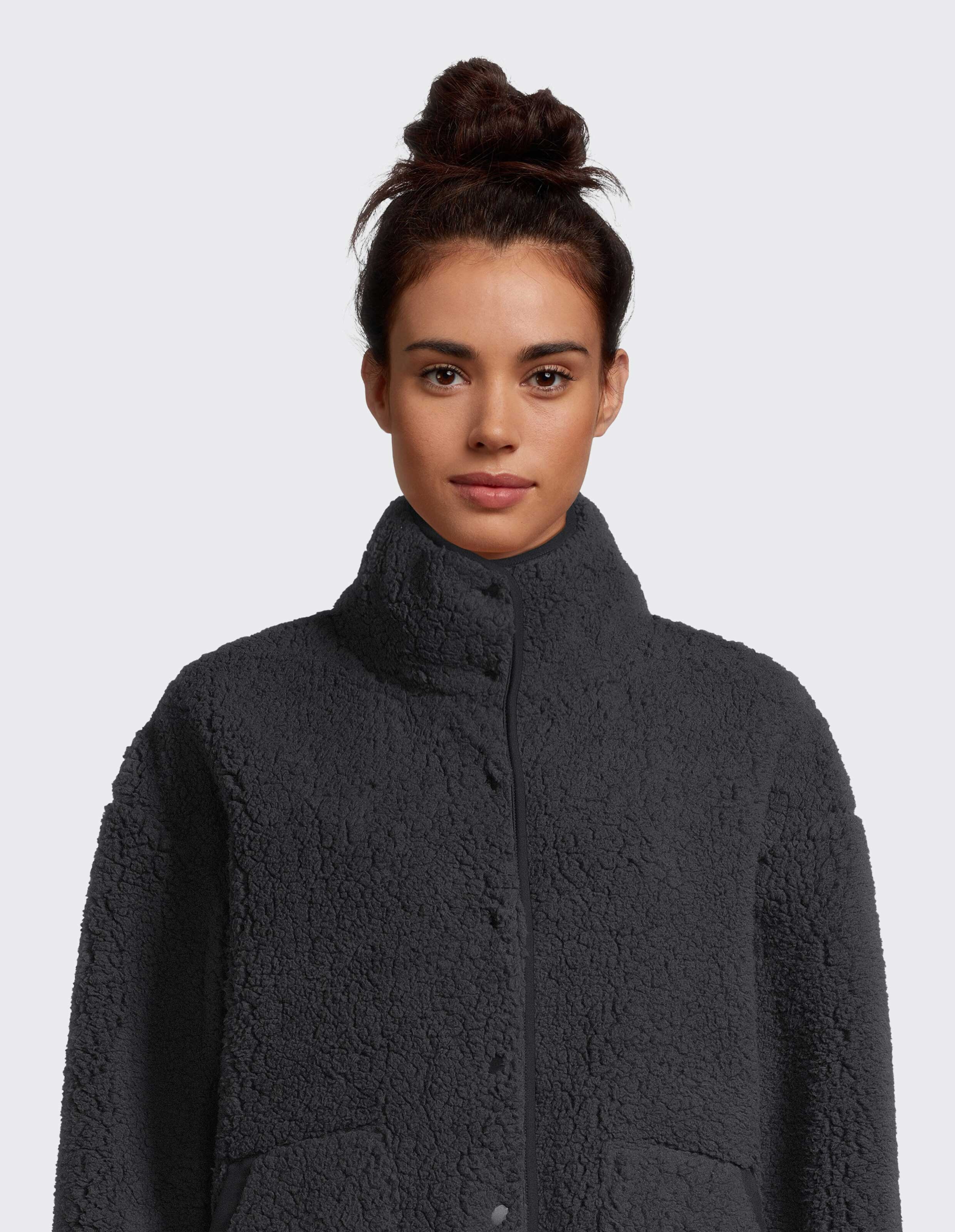 Frau trägt eine kuschelige dunkelgraue Teddyfleecejacke mit hohem Kragen.
