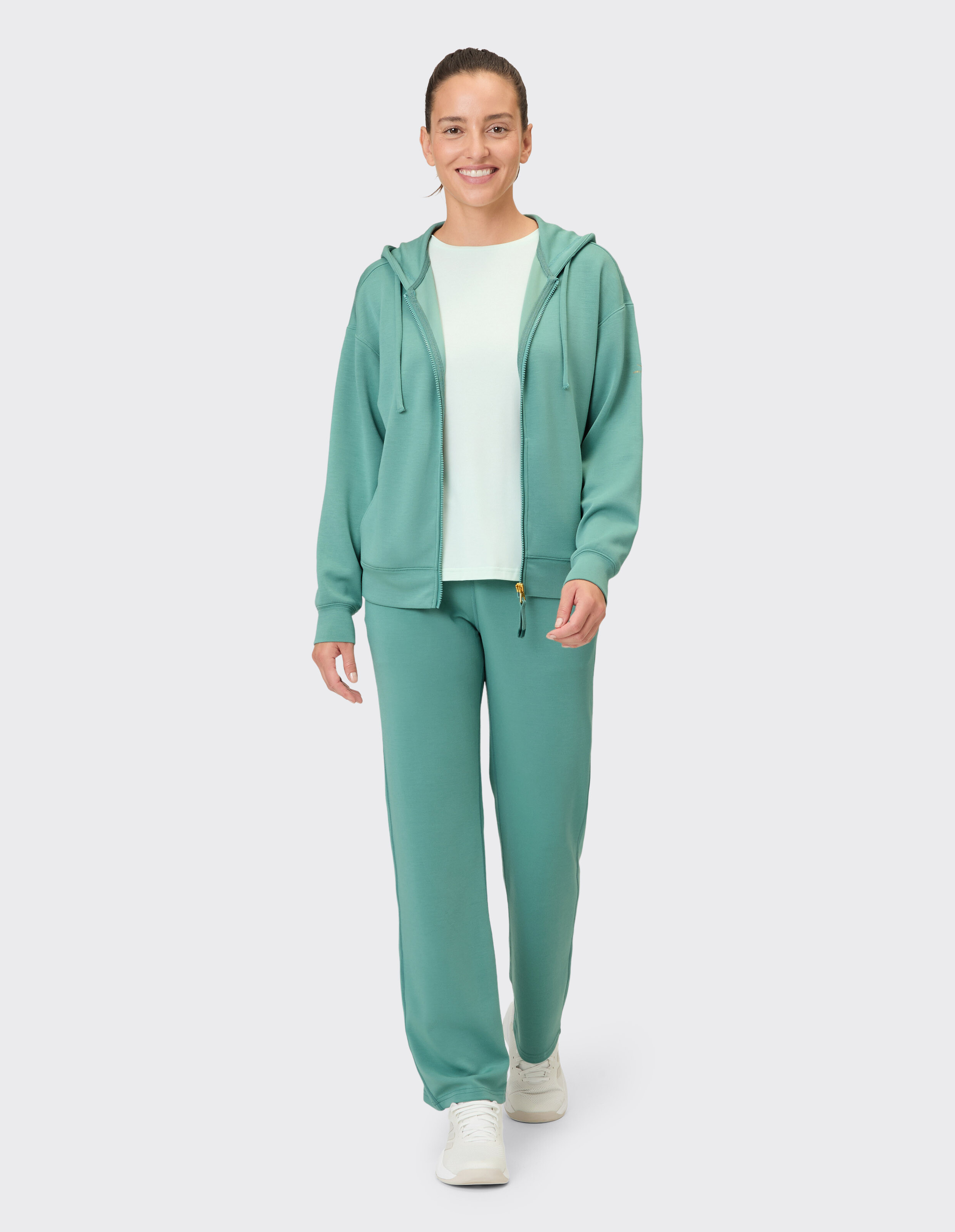 Frau trägt einen grünen Caylee-Hoodie von Venice Beach Sweatjacke und eine passende Lounge-Hose.