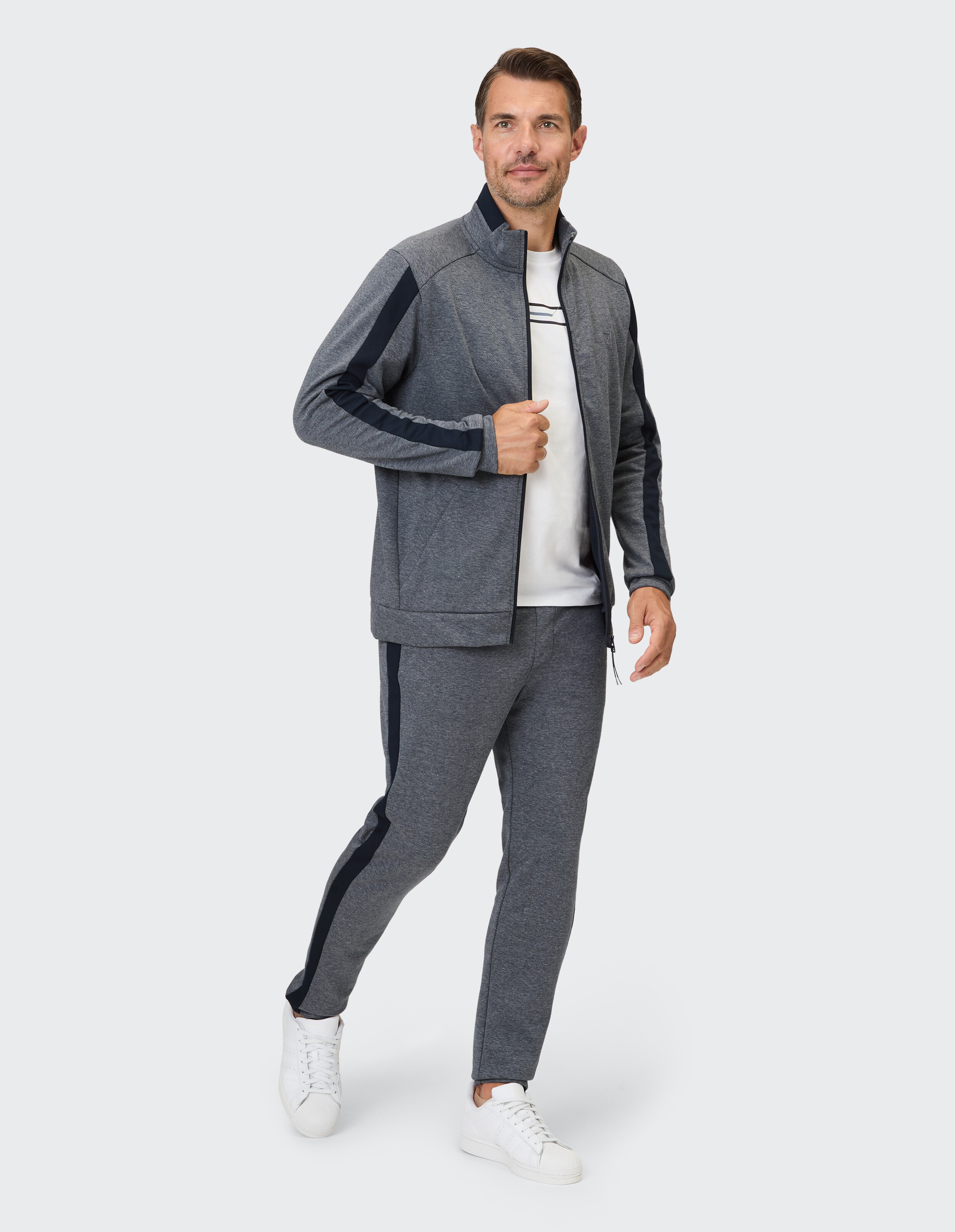 Mann in einem grauen Sport-Trainingsanzug mit marineblauen Akzenten, perfekt für Freizeitkleidung.