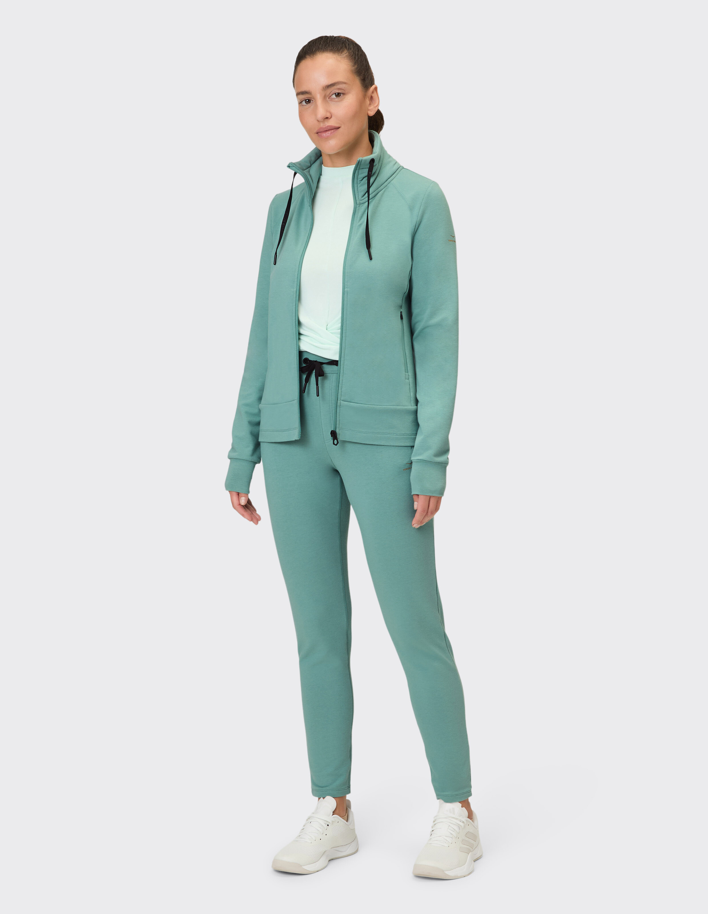Frau im mintgrünen Freizeit-Trainingsanzug mit Reißverschlussjacke und passender Hose.