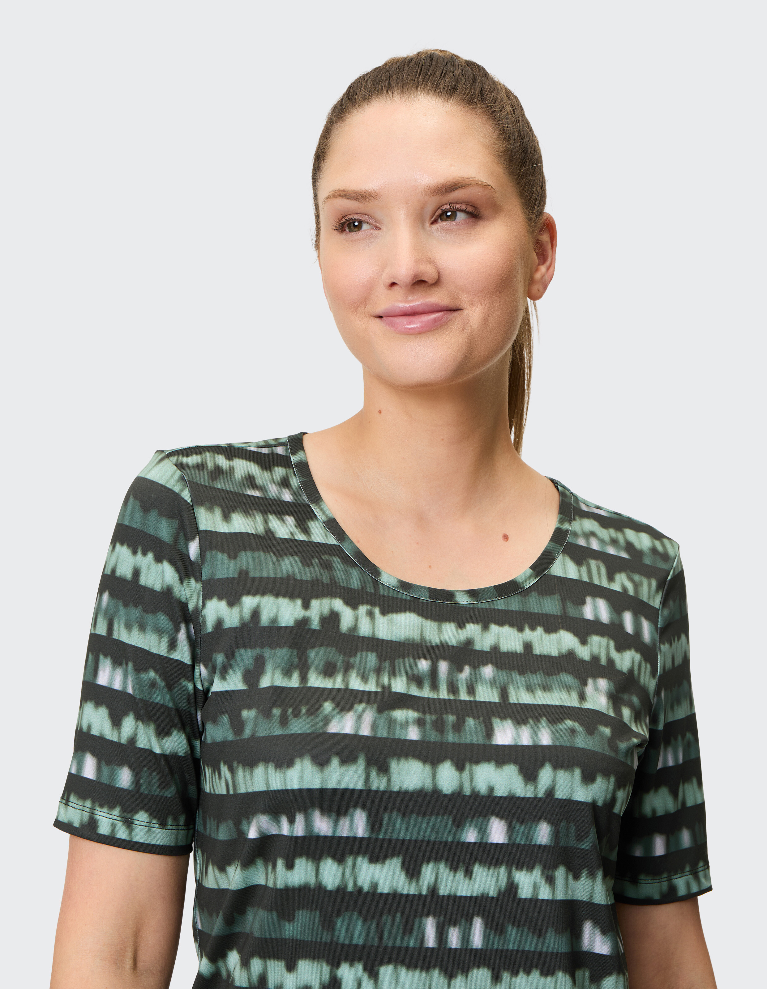 Kurzärmeliges T-Shirt mit grün-schwarz gestreiftem, verschwommenem Muster und rundem Ausschnitt, modern und sportlich designt.