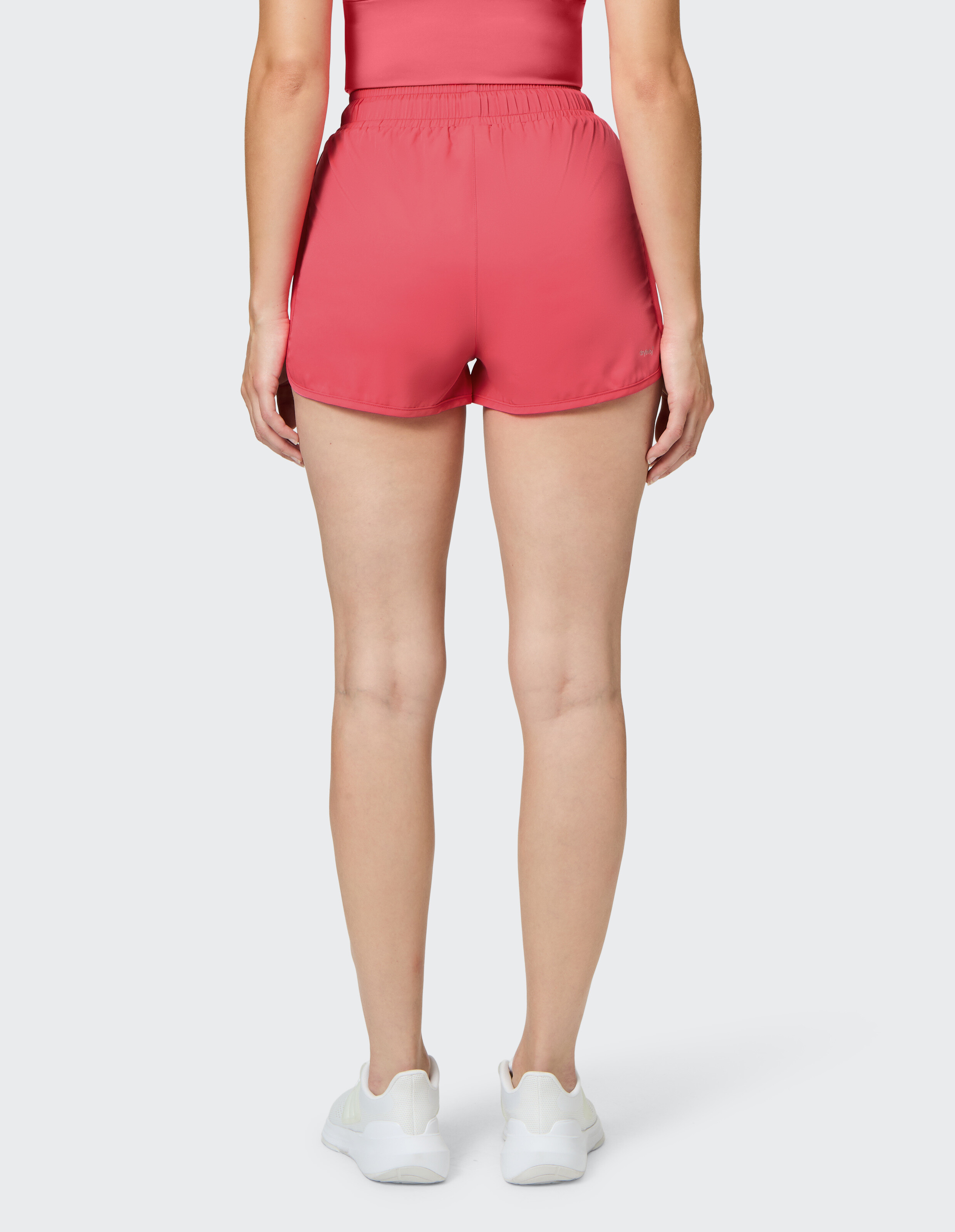 Rückansicht einer Frau, die rosa lässige Sportshorts zum Faulenzen oder Sport trägt.