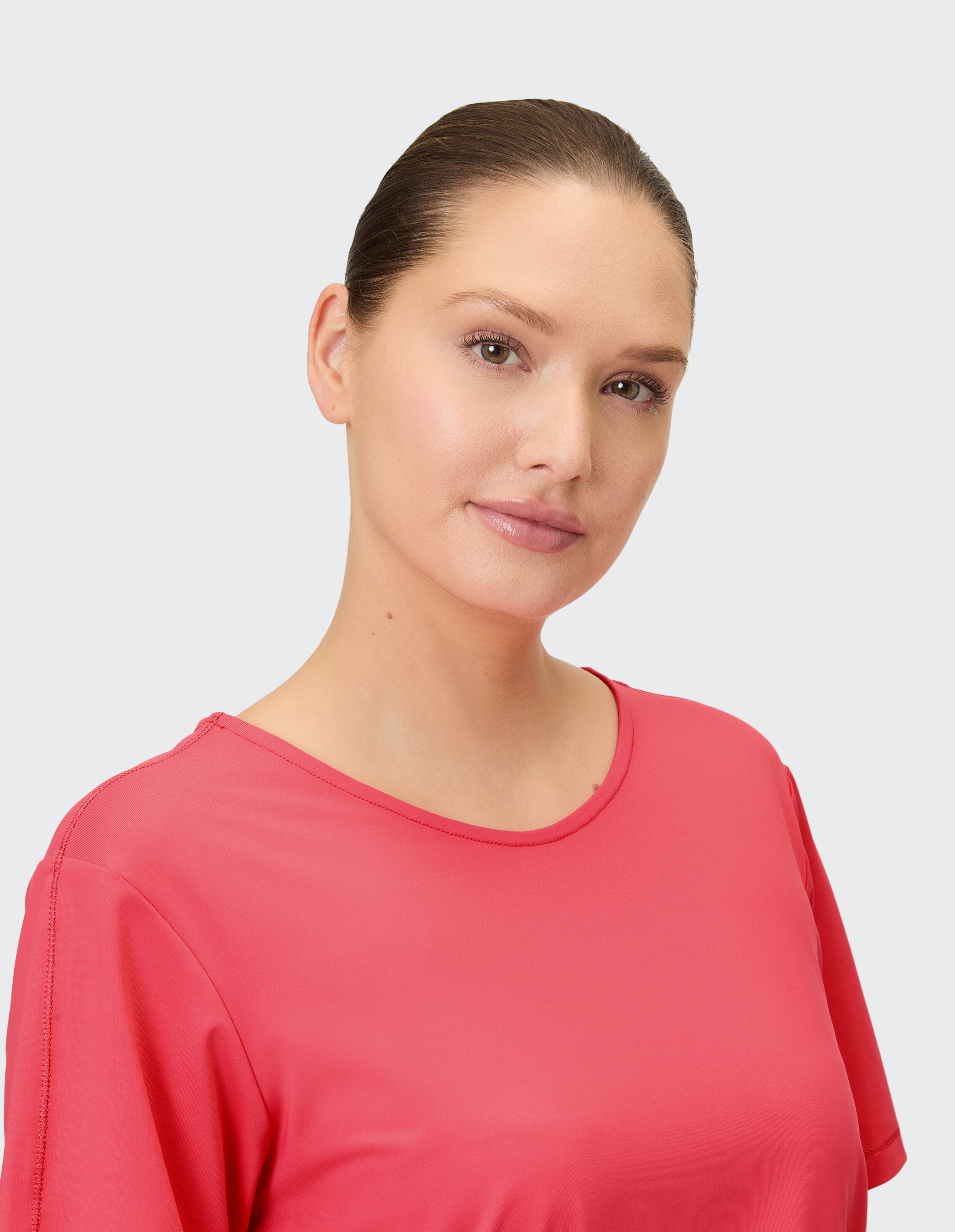 Ein Model trägt ein pinkes T-Shirt mit Rundhalsausschnitt.