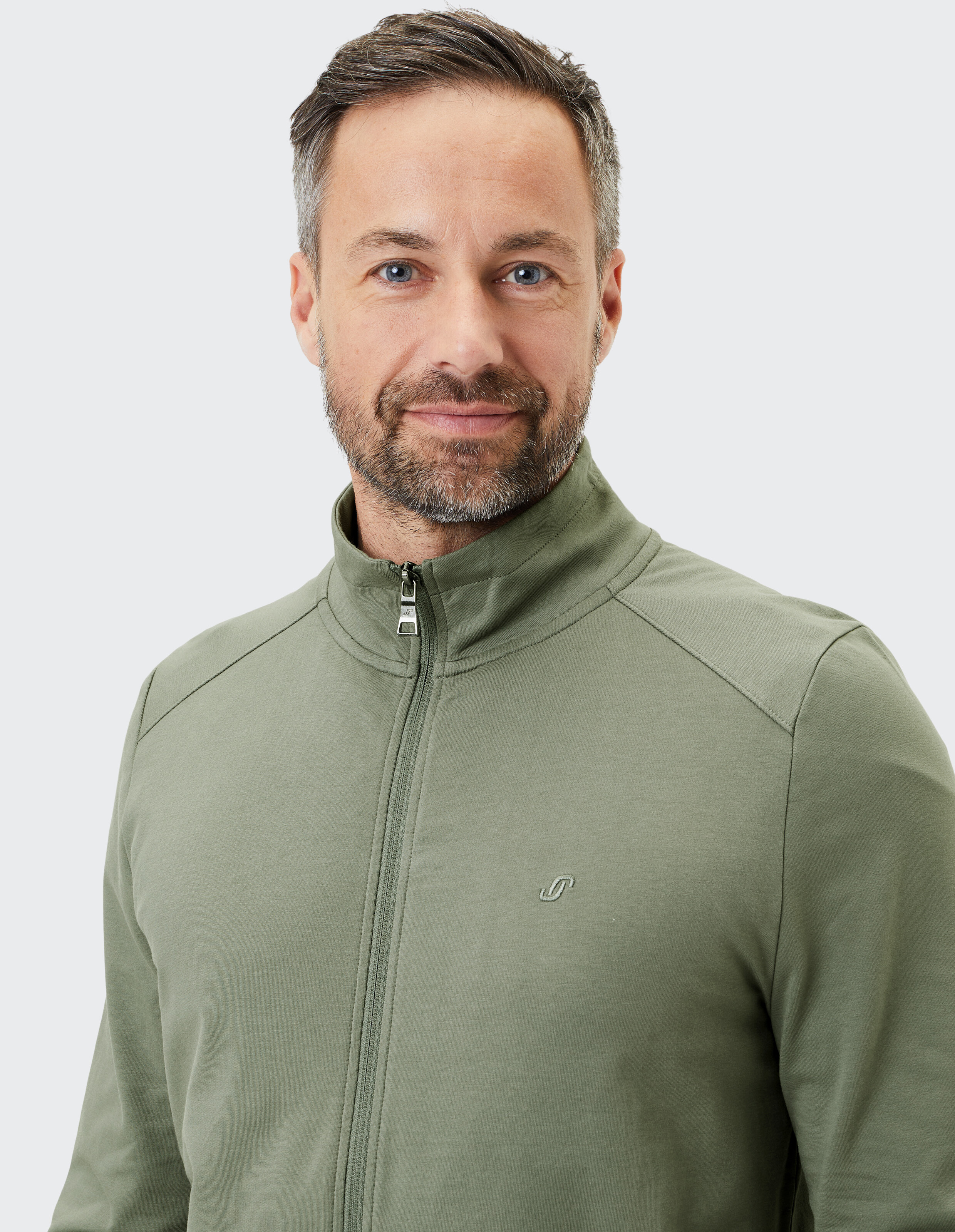 Grüne Unisex-Freizeitjacke mit durchgehendem Reißverschluss, zwei Reißverschlusstaschen und hohem Kragen aus leichtem Material.