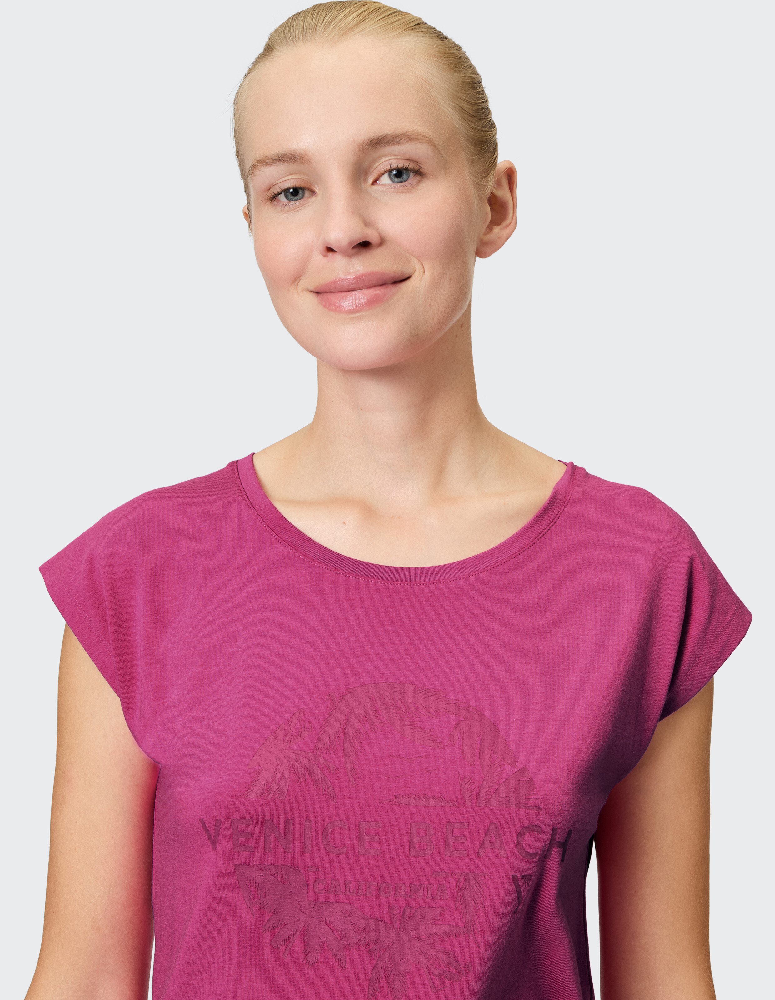 Frau trägt ein lässiges magentafarbenes Venice Beach-Grafik-T-Shirt für alltäglichen Komfort.