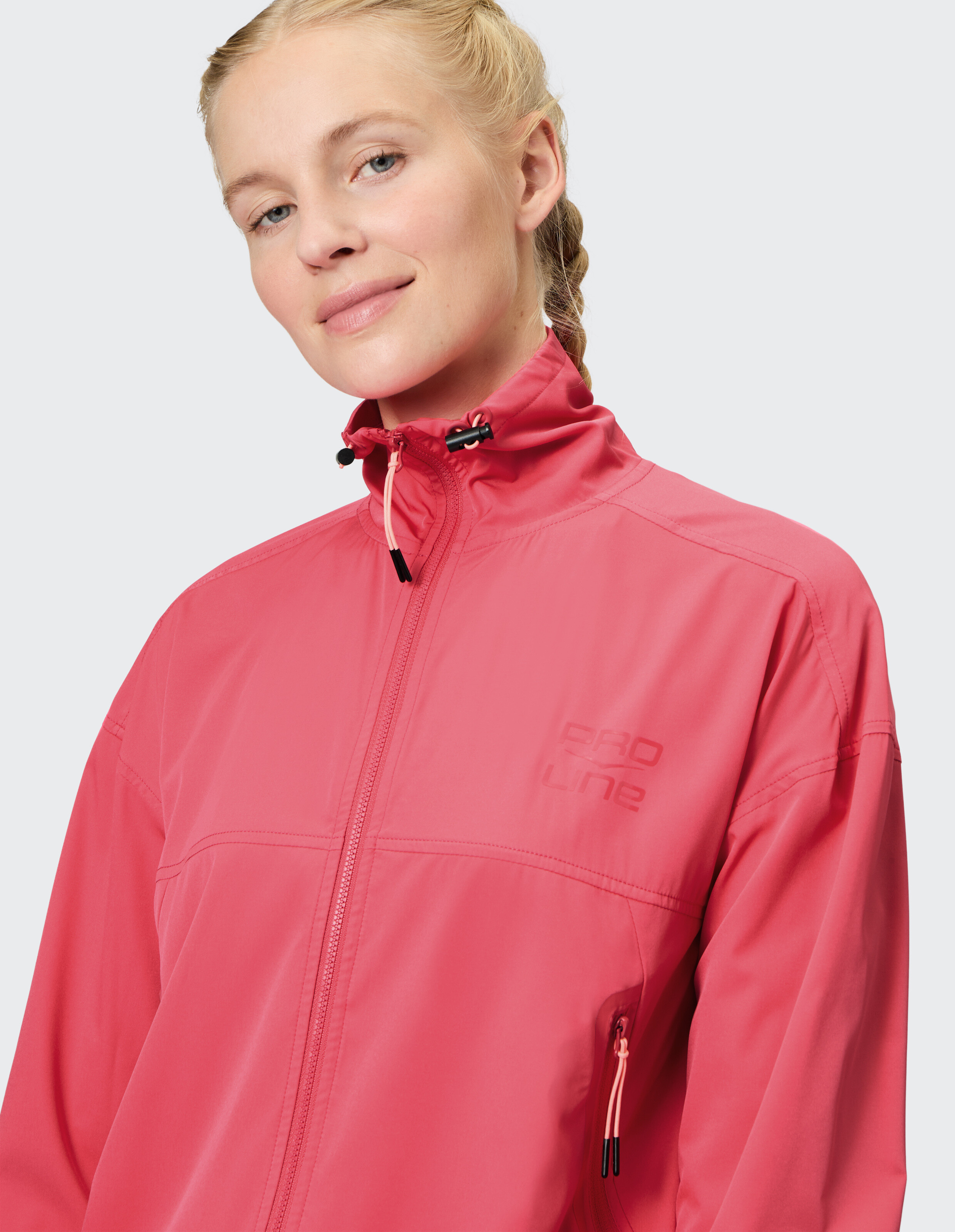 Nahaufnahme einer Frau in einer rosa Freizeitjacke mit hohem Kragen und Reißverschluss.
