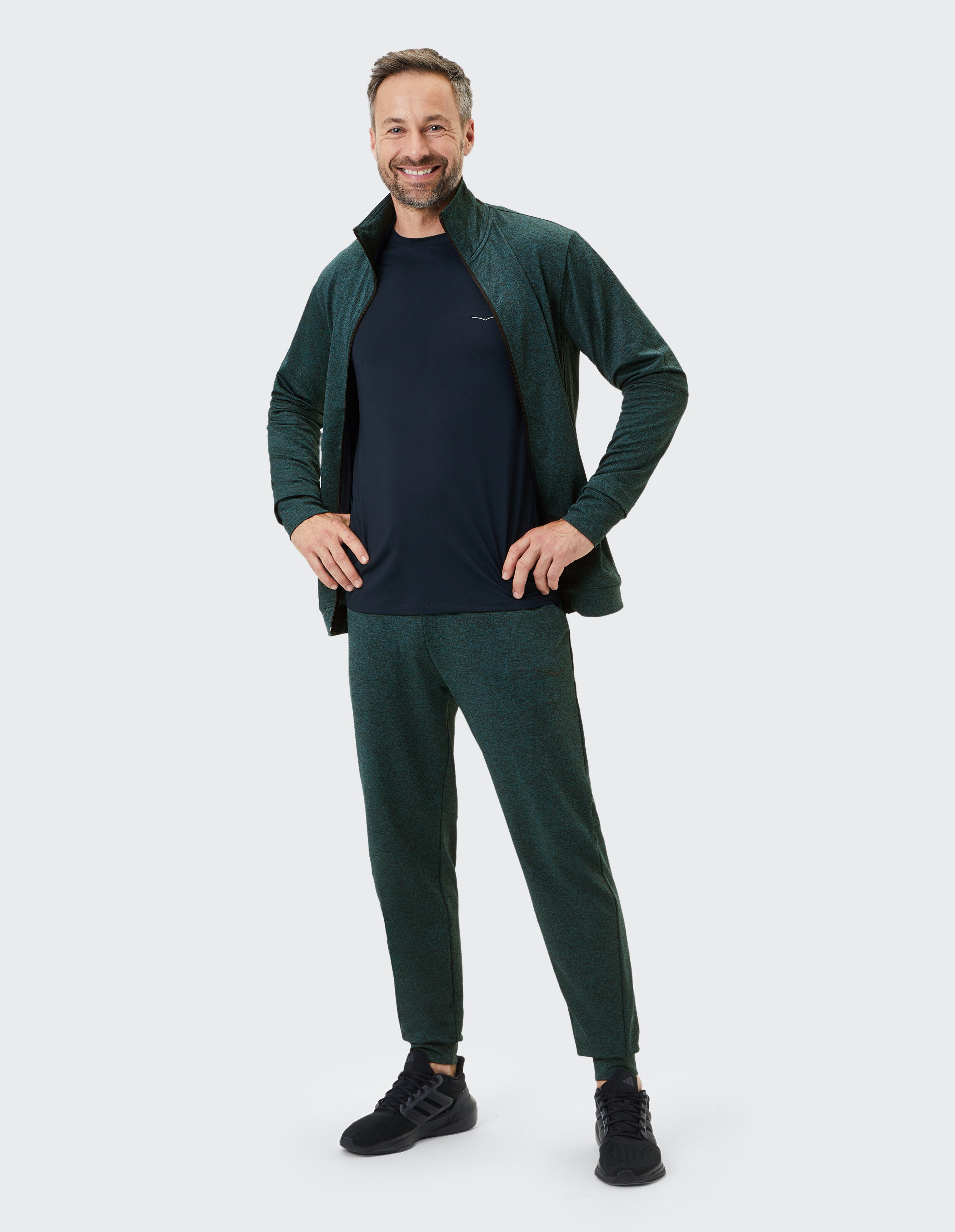 Mann in grüner Sportjacke und Hose, perfekt für Freizeitkleidung oder zum Faulenzen.