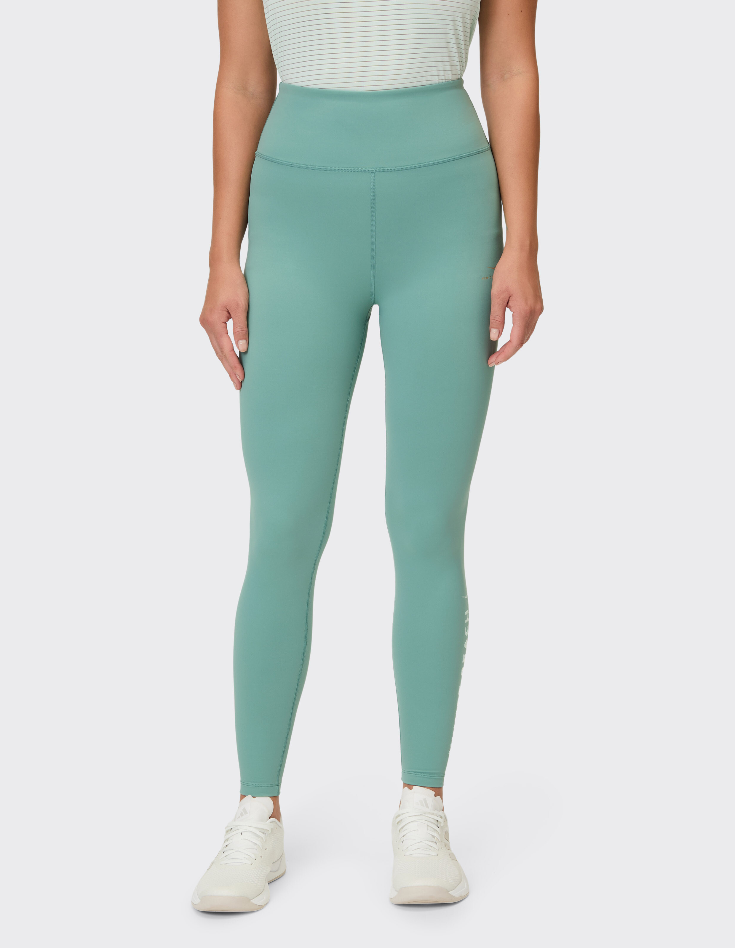 Frau trägt salbeigrüne Leggings mit hoher Taille zum lässigen Faulenzen oder als Aktivkleidung.