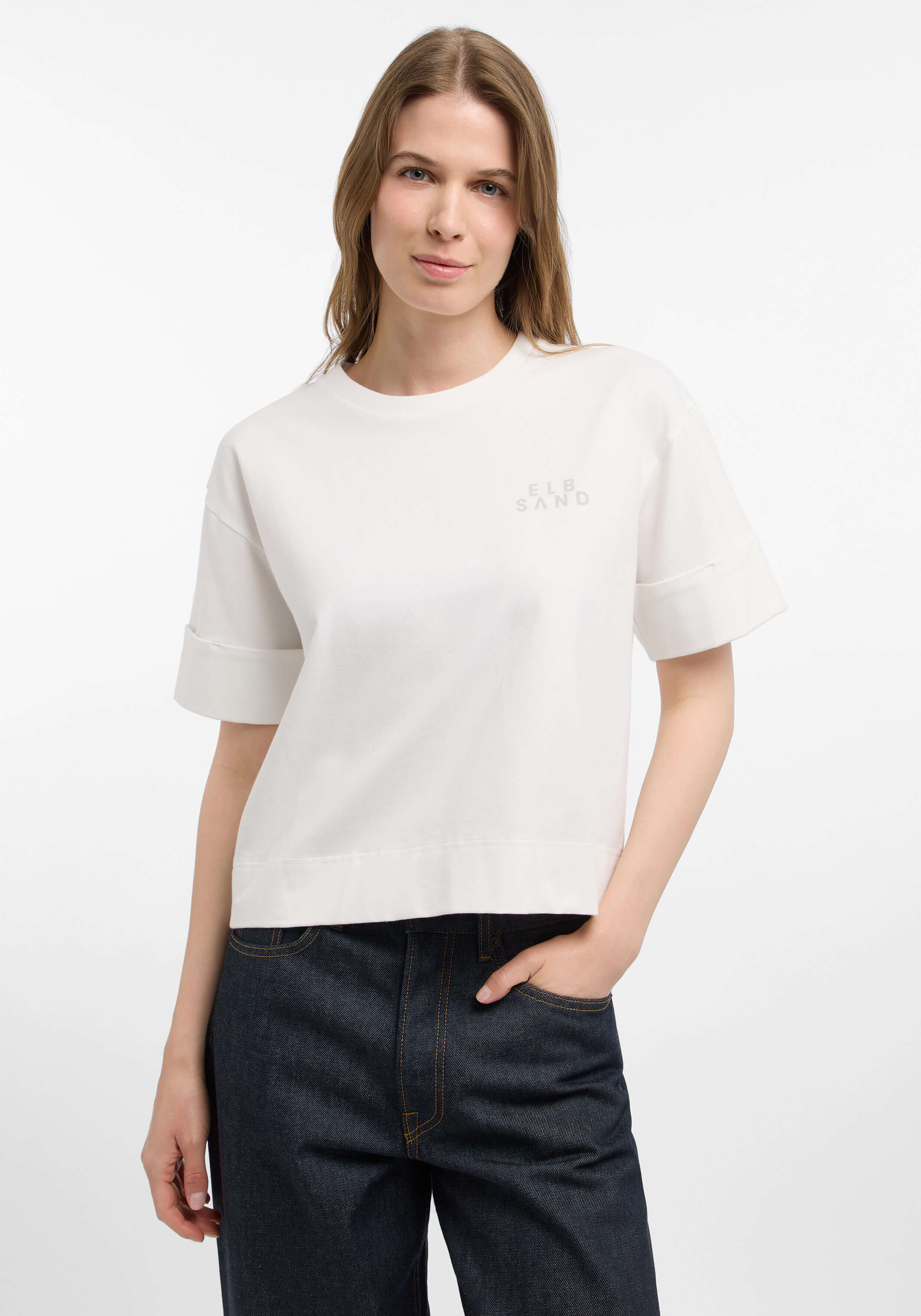 Frau trägt ein weißes, lässiges Kurzarm-Sweatshirt von ELBSAND mit Rollbündchen.