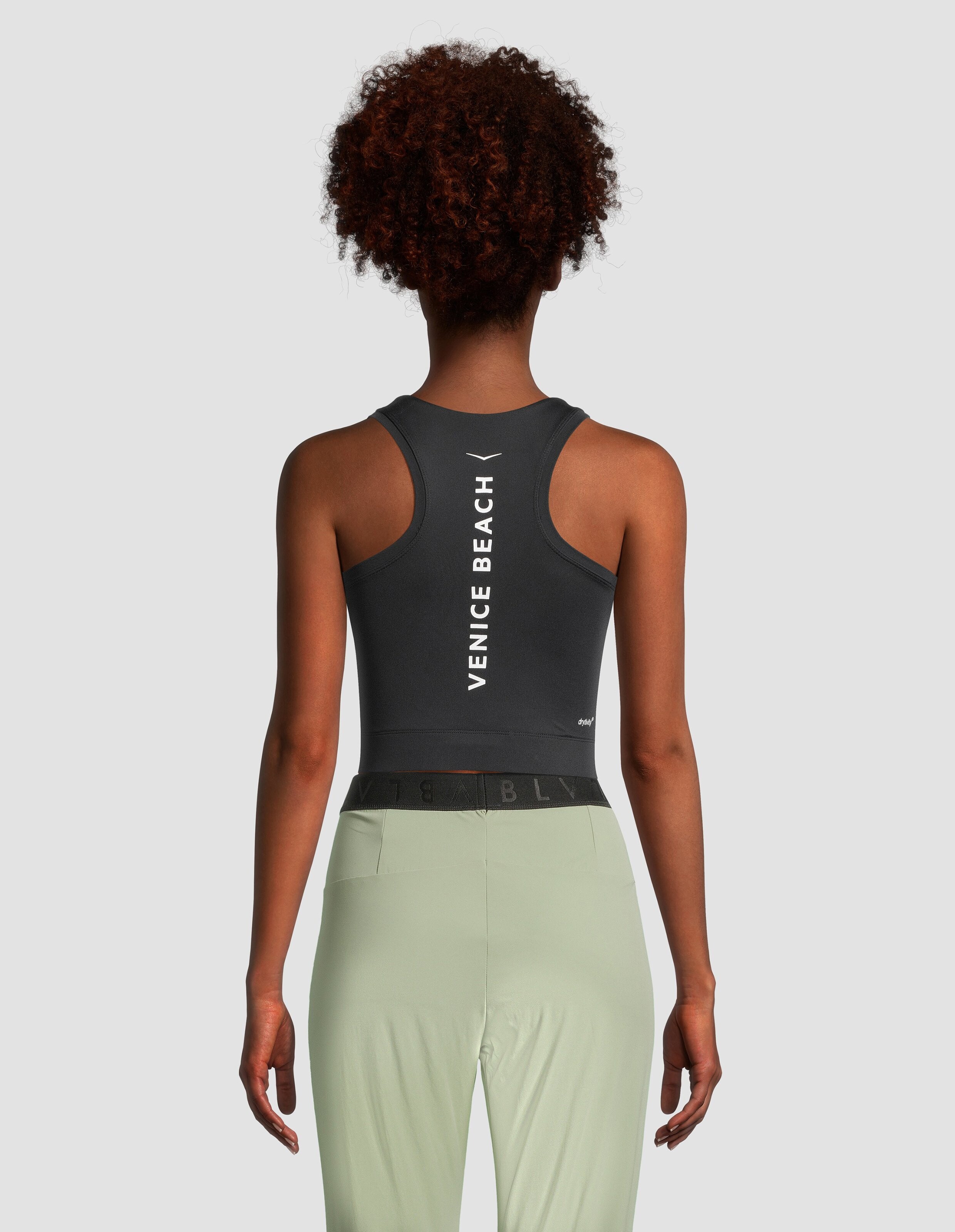 Rückansicht einer Frau, die ein schwarzes Racerback-Crop-Top von Venice Beach Editha trägt.