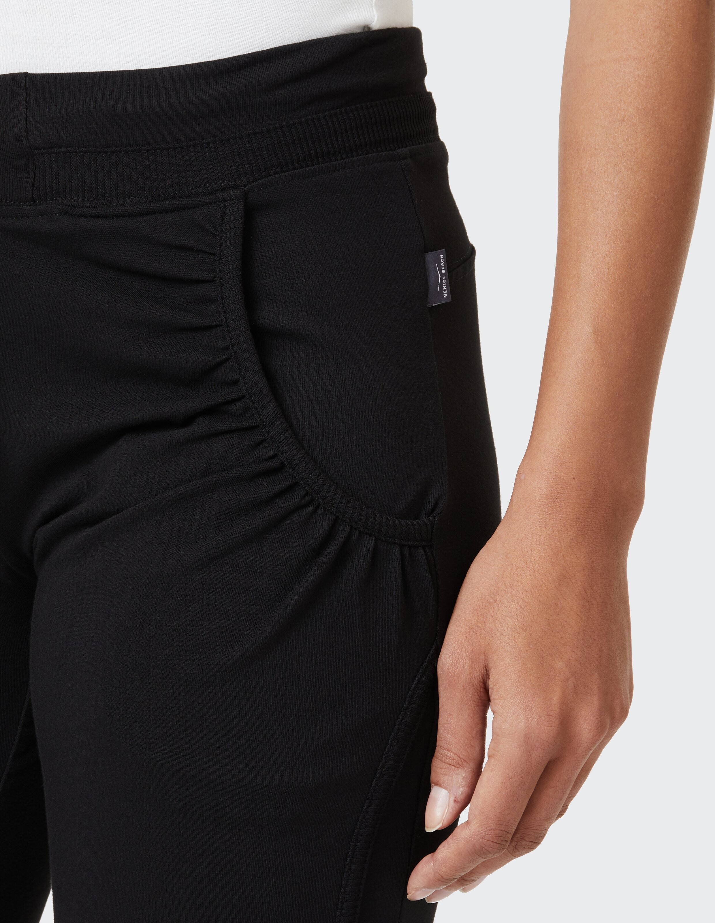 Nahaufnahme einer schwarzen Freizeithose mit gerafften Seitentaschen und elastischem Bund.