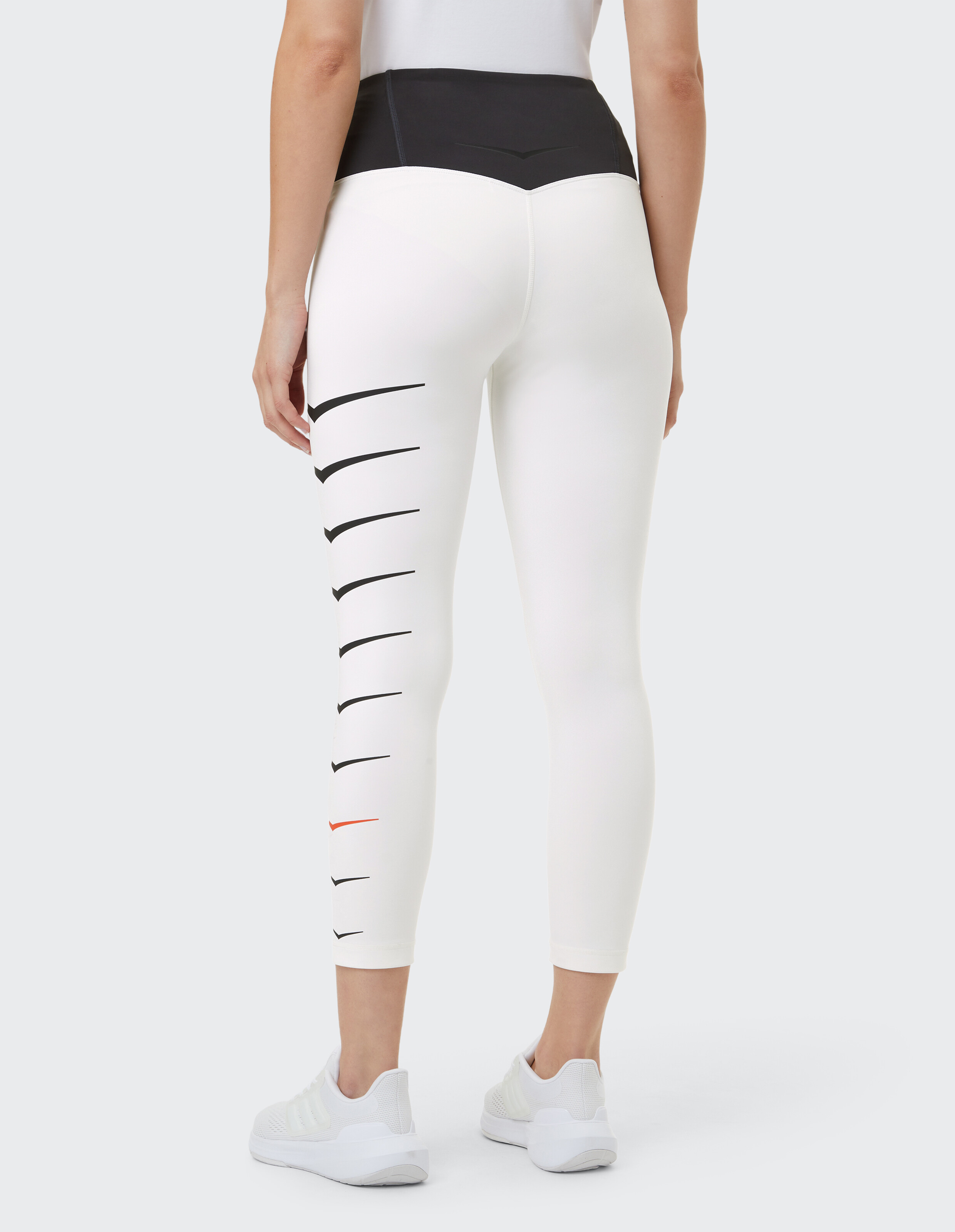 Frau trägt weiße Leggings mit hoher Taille und schwarzen Swoosh-Logos für einen lässigen, sportlichen Stil.