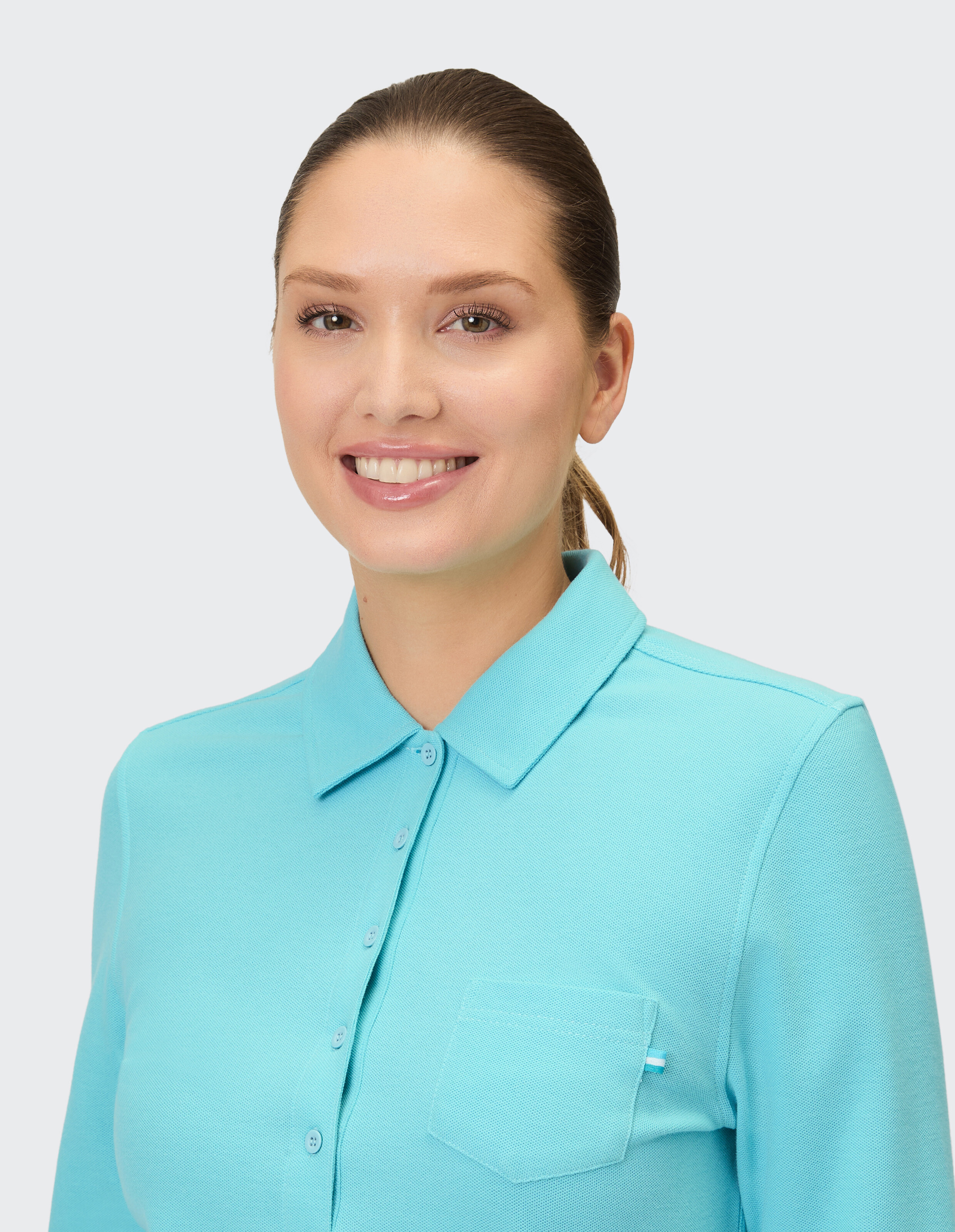 Lächelnde Frau trägt ein hellblaues Poloshirt mit Taschendetail.
