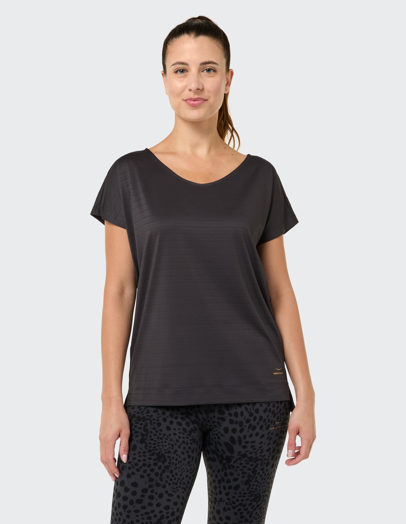 Frau in einem schwarzen Kurzarm-Top gepaart mit Leggings mit Leopardenmuster.