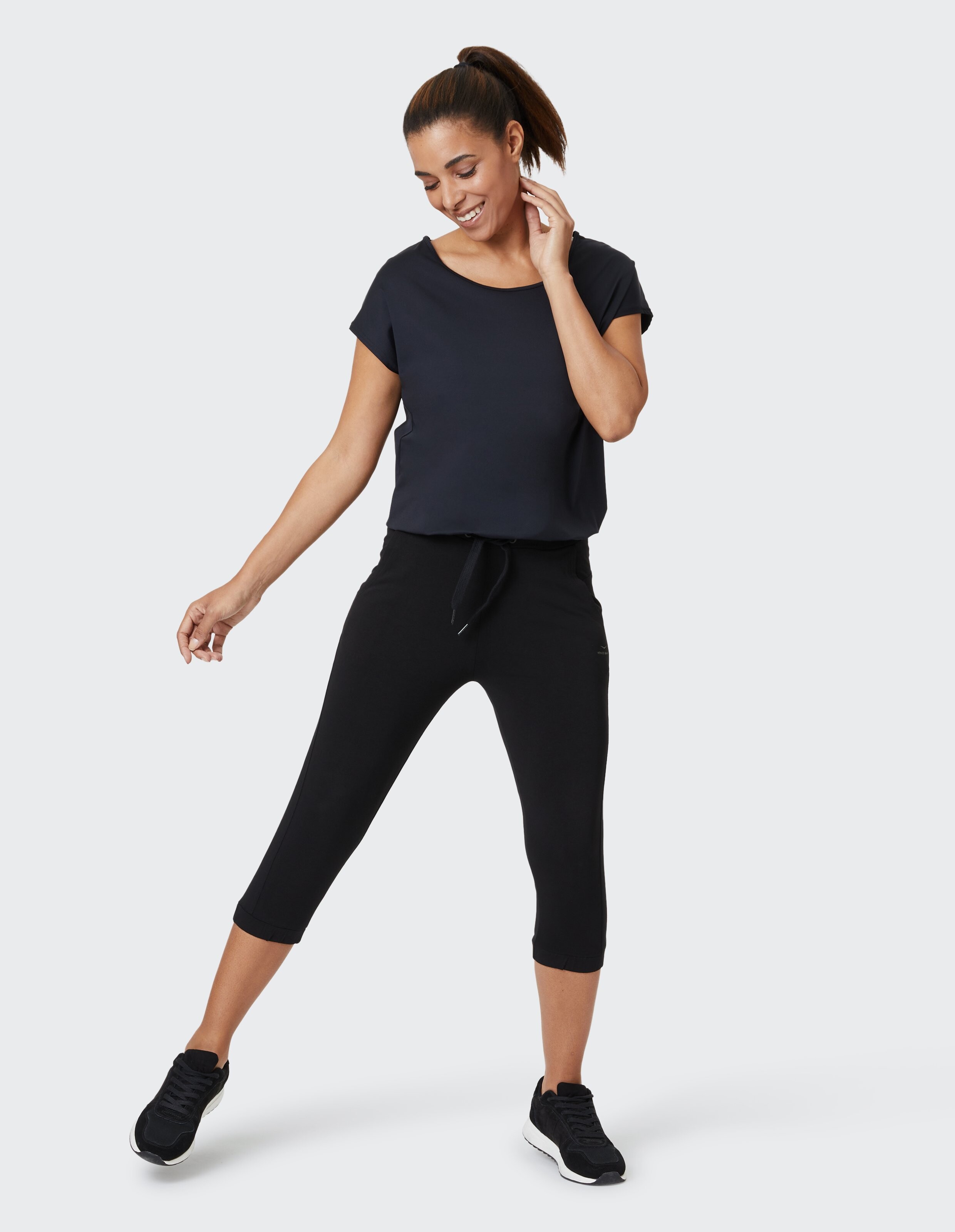 Frau trägt ein schwarzes Freizeit-T-Shirt und kurze Lounge-Hosen für einen bequemen, stilvollen Look.