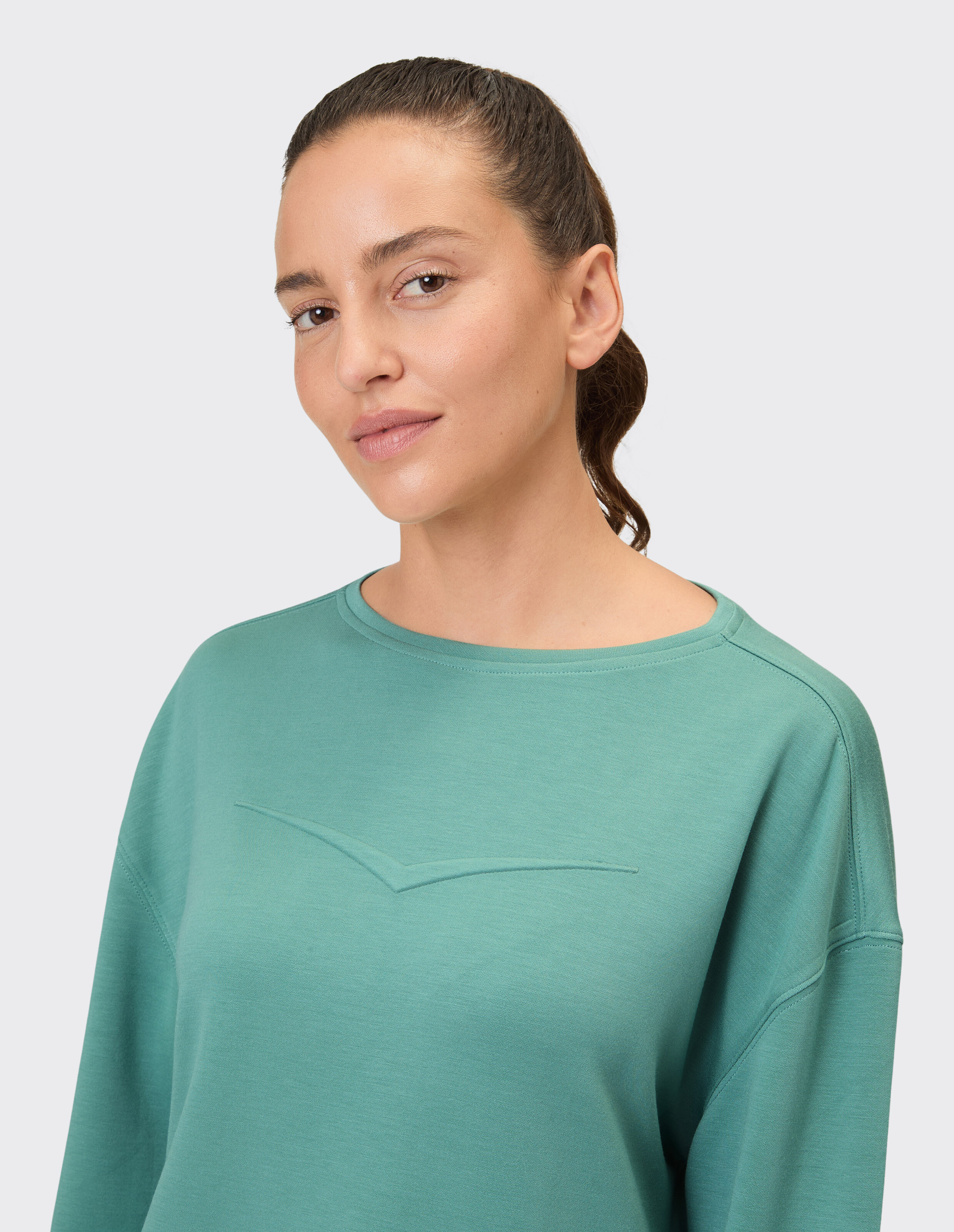 Frau trägt ein gemütliches grünes April-Sweatshirt von Venice Beach zum lässigen Faulenzen.