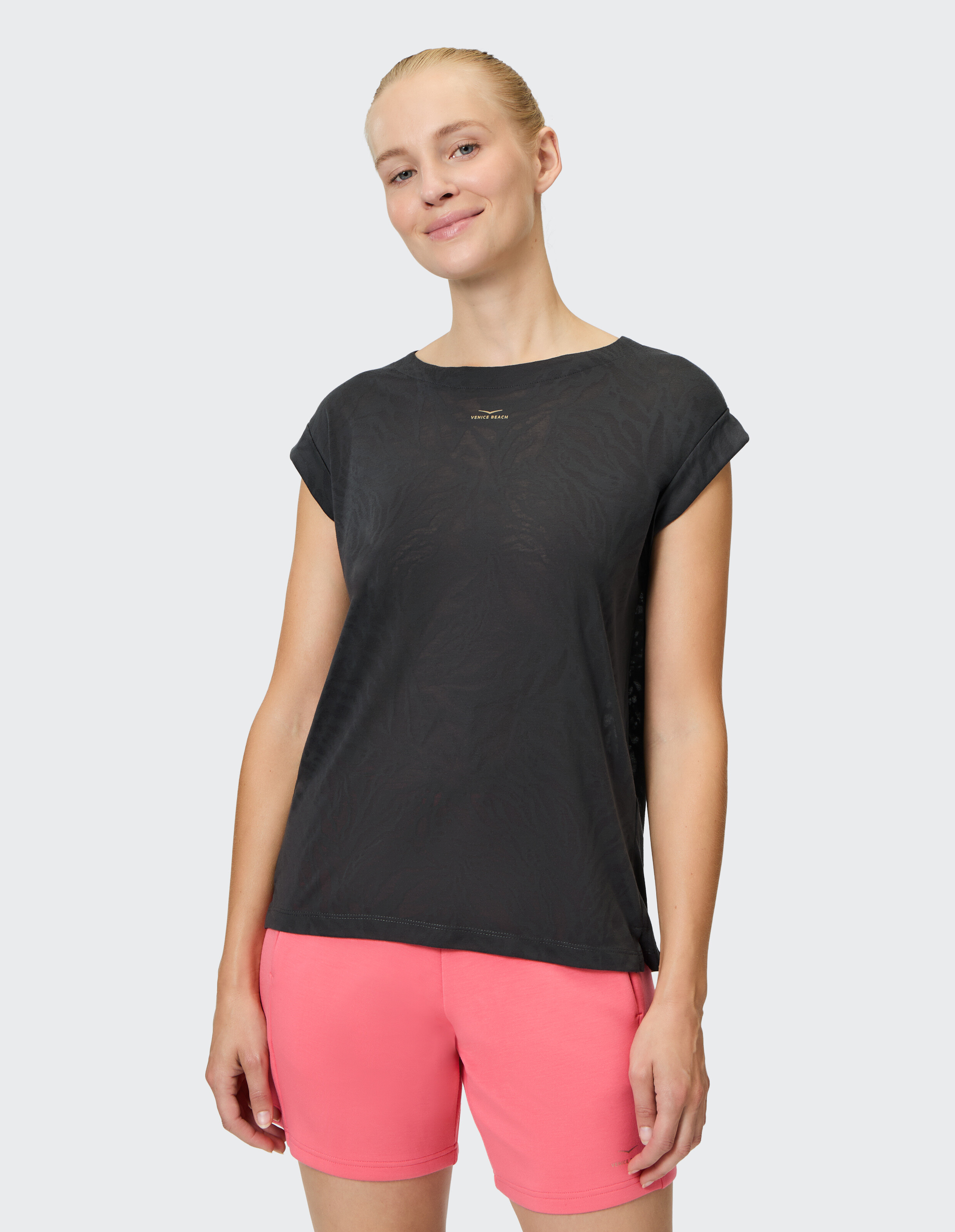 Frau trägt ein schwarz gemustertes Freizeit-T-Shirt und rosa Shorts für einen bequemen Look.