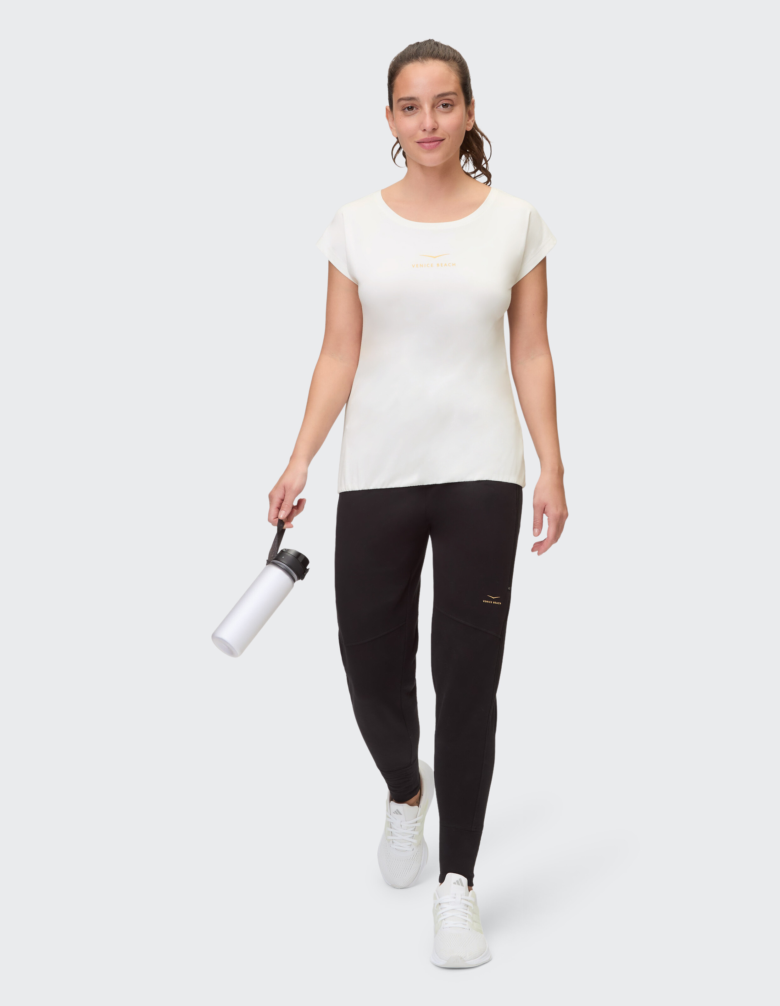 Frau trägt das weiße Venice Beach Kurzarmshirt Wonder und schwarze Jogginghosen.