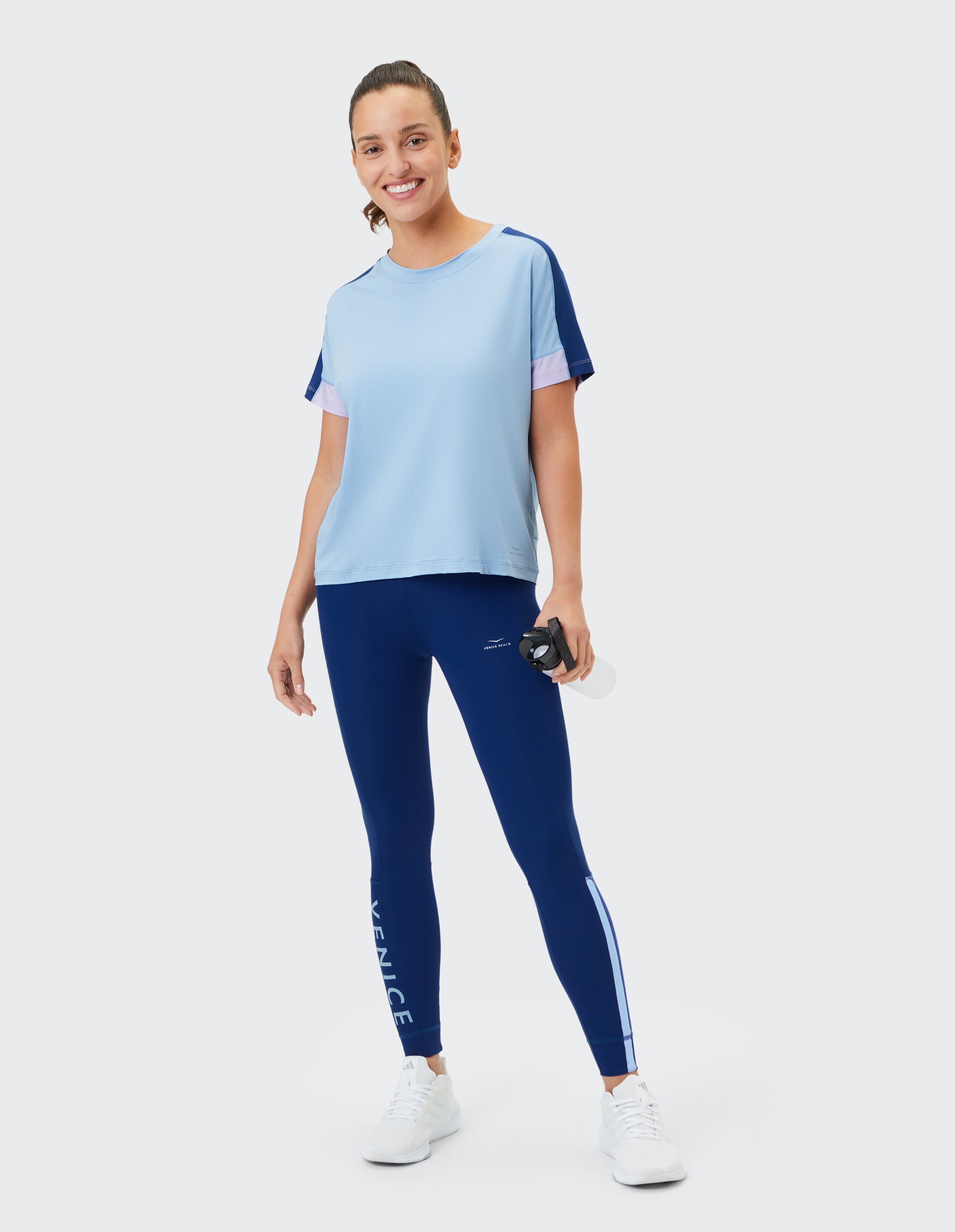 Frau trägt ein hellblaues T-Shirt und dunkelblaue Leggings für einen bequemen, lässigen Workout-Look.