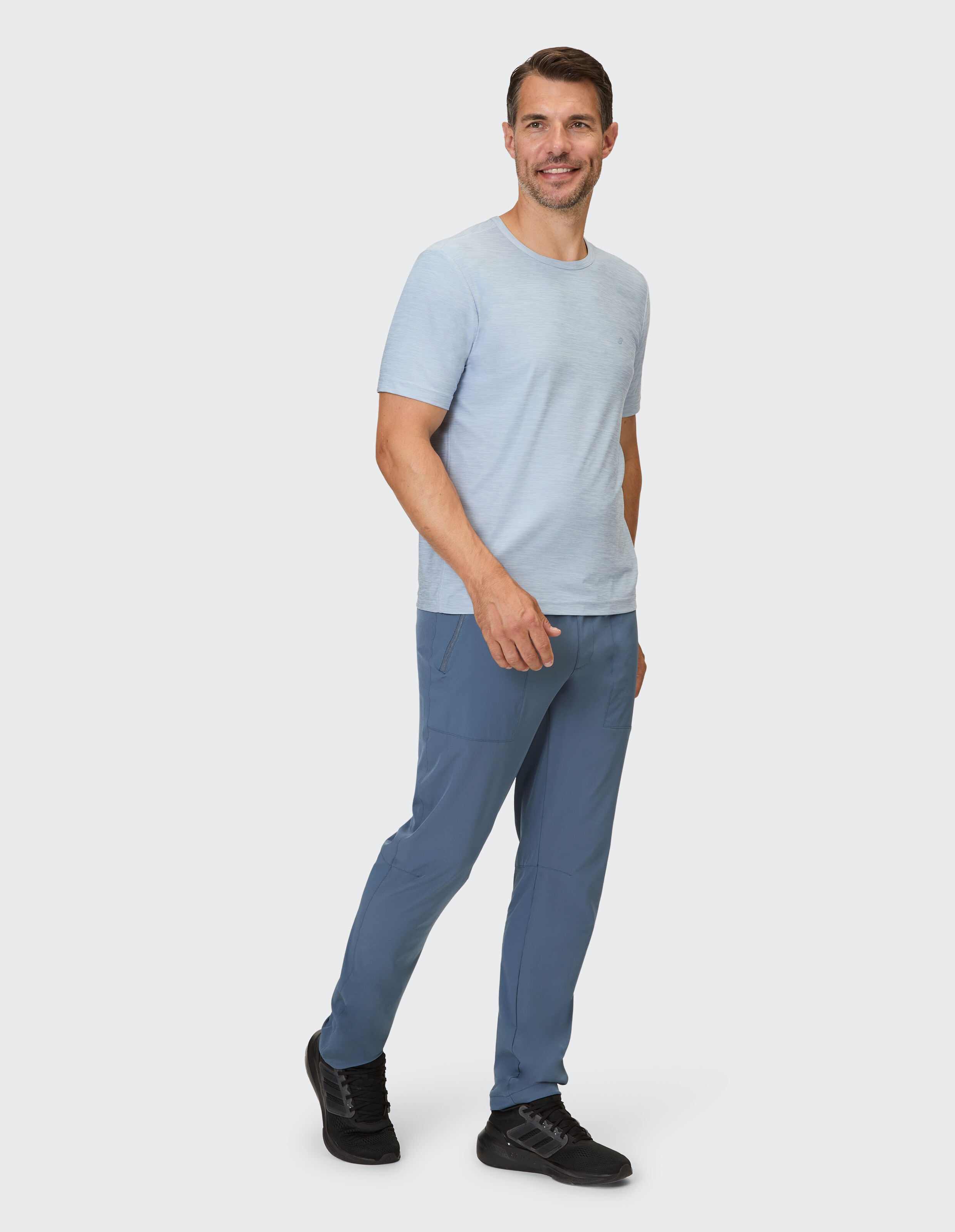 Mann in hellblauem T-Shirt und blauer Freizeithose, der einen entspannten Stil zeigt.