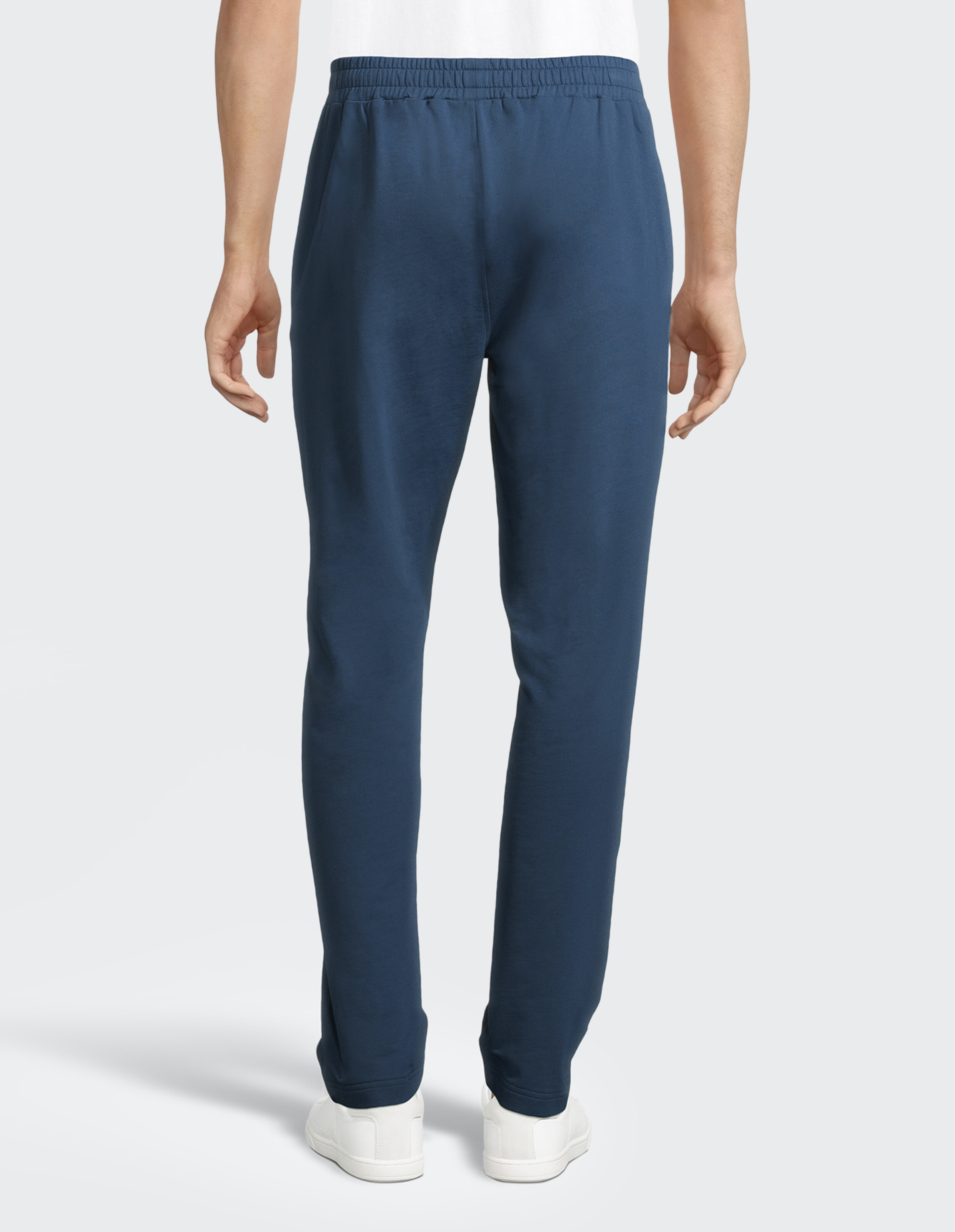 Rückansicht einer Person in blauer Jogginghose und weißen Turnschuhen