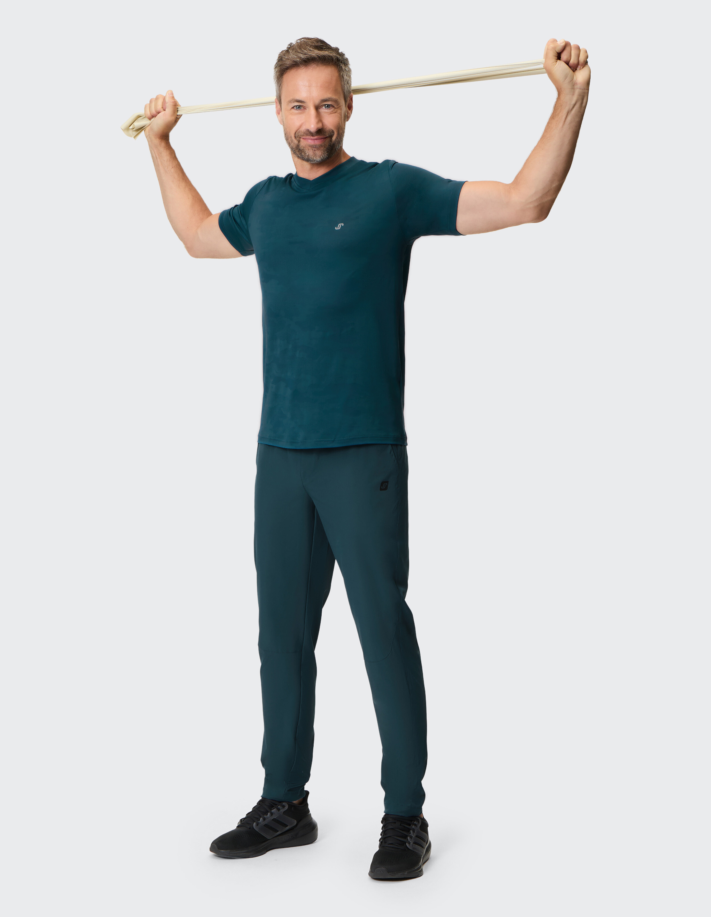 Mann in blaugrüner Freizeitkleidung mit tailliertem T-Shirt und Jogginghose.