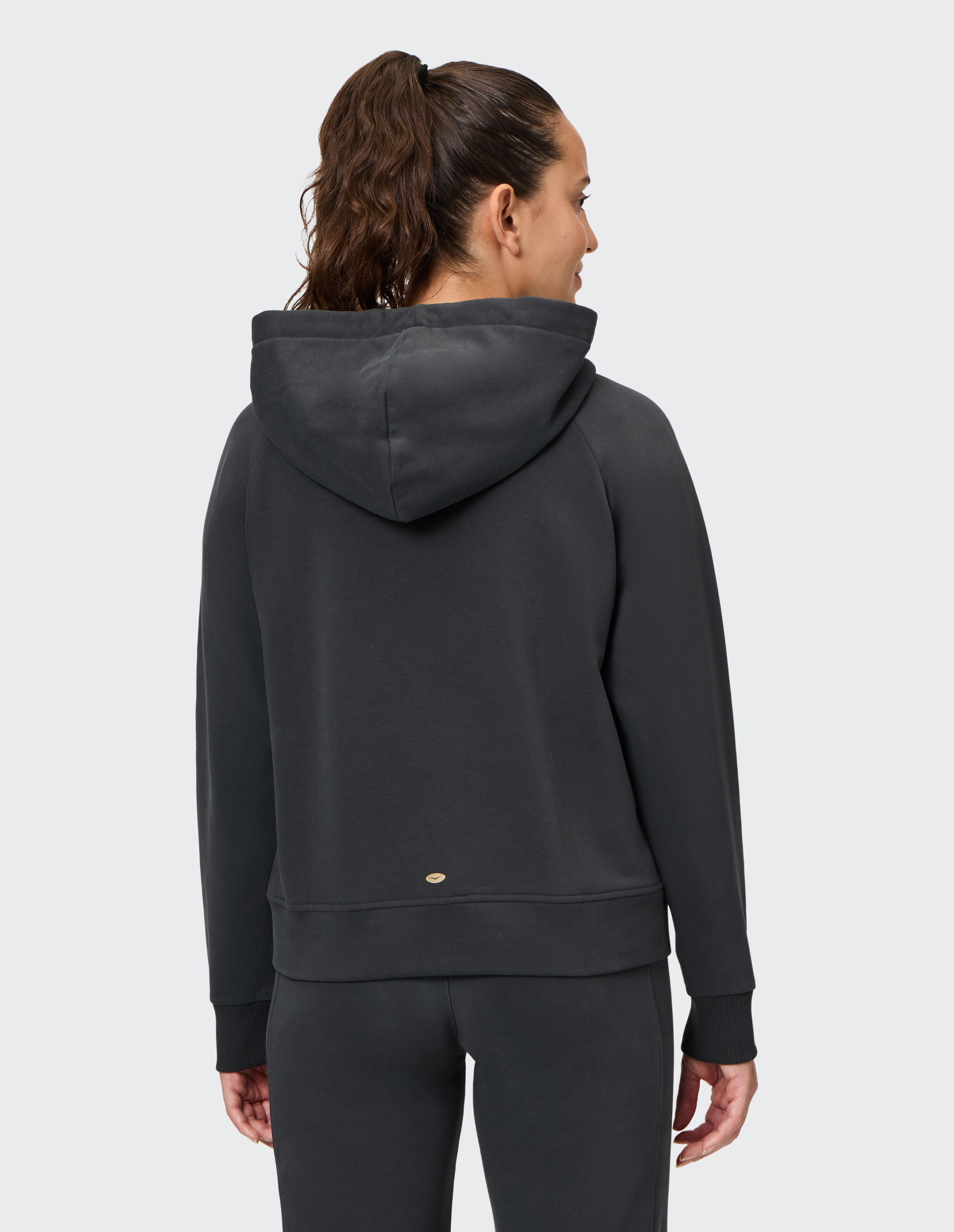 Frau trägt einen kuscheligen dunkelgrauen ELBSAND-Hoodie, Rückansicht, perfekt für lässige Loungewear.