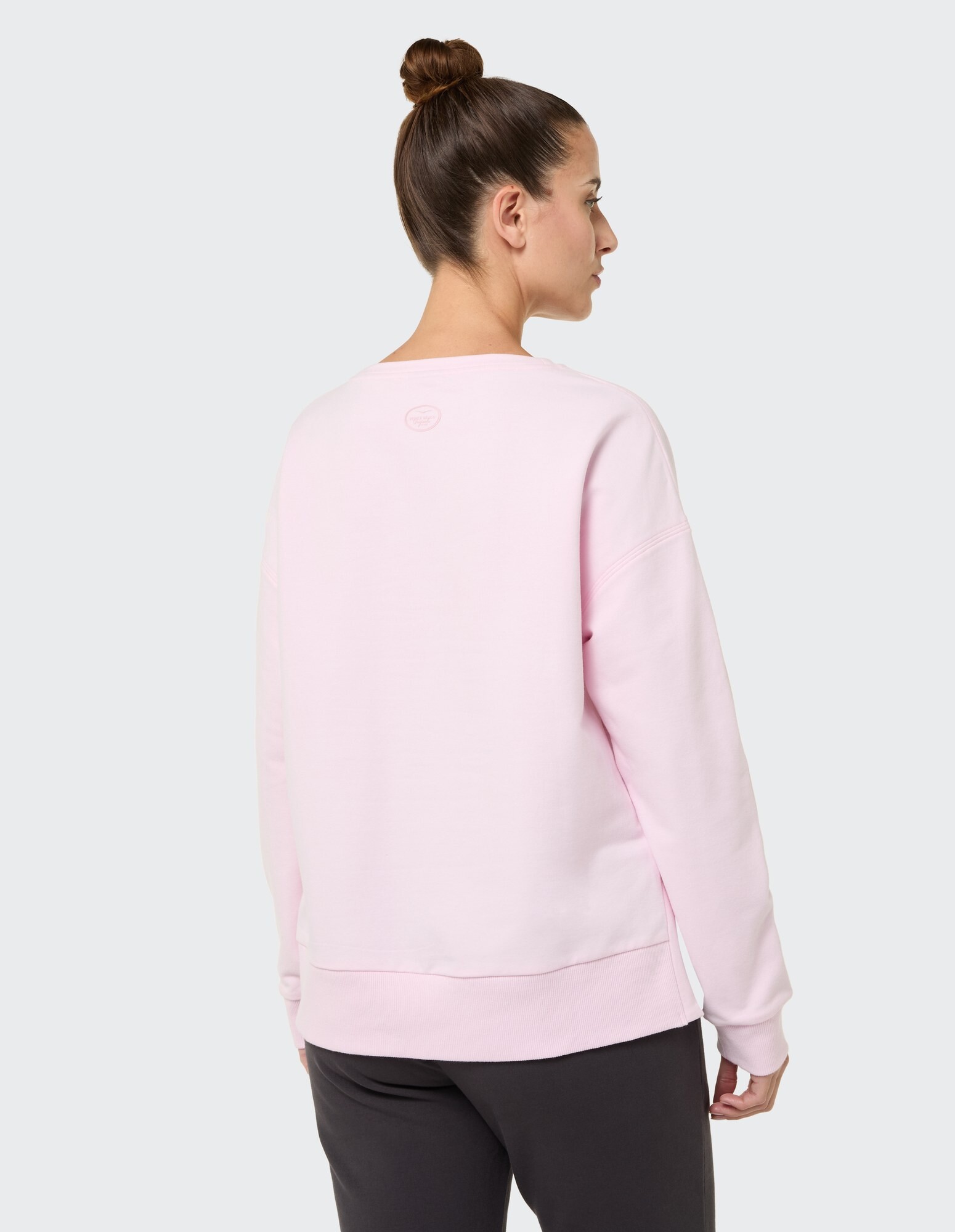 Rückansicht einer Frau in einem rosa lässigen Sweatshirt, perfekt zum Entspannen.