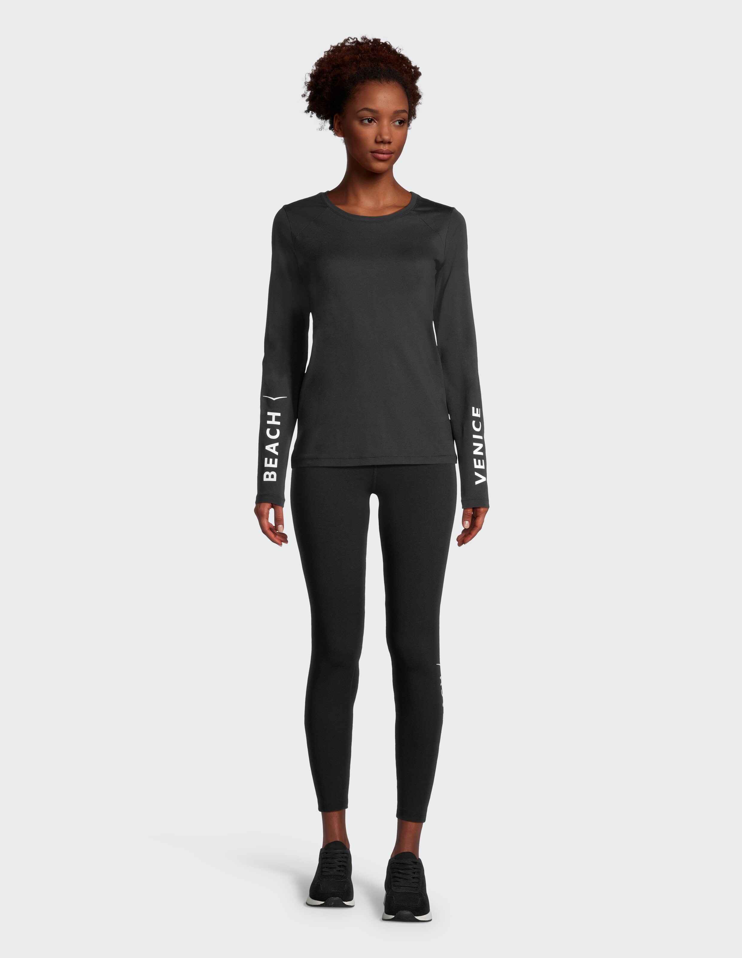 Frau in schwarzem Langarm-Top und Leggings, stilvolle Freizeitkleidung.