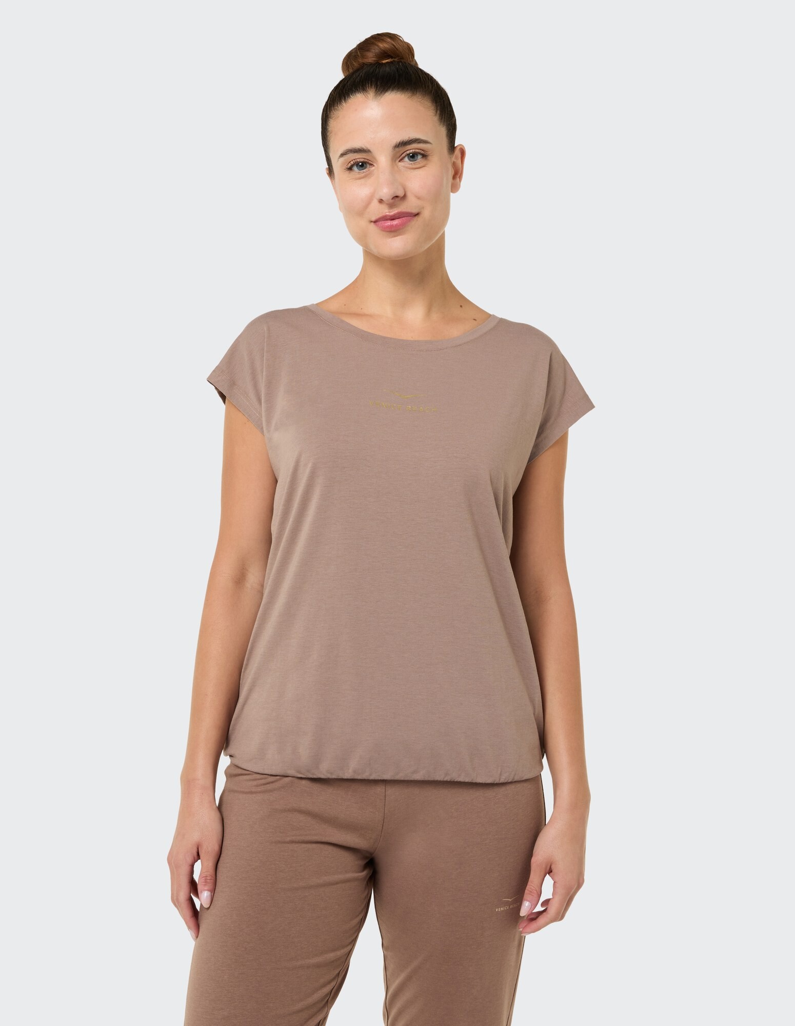 Das Model trägt ein gemütliches braunes T-Shirt und eine passende Hose, perfekt für Freizeitkleidung.