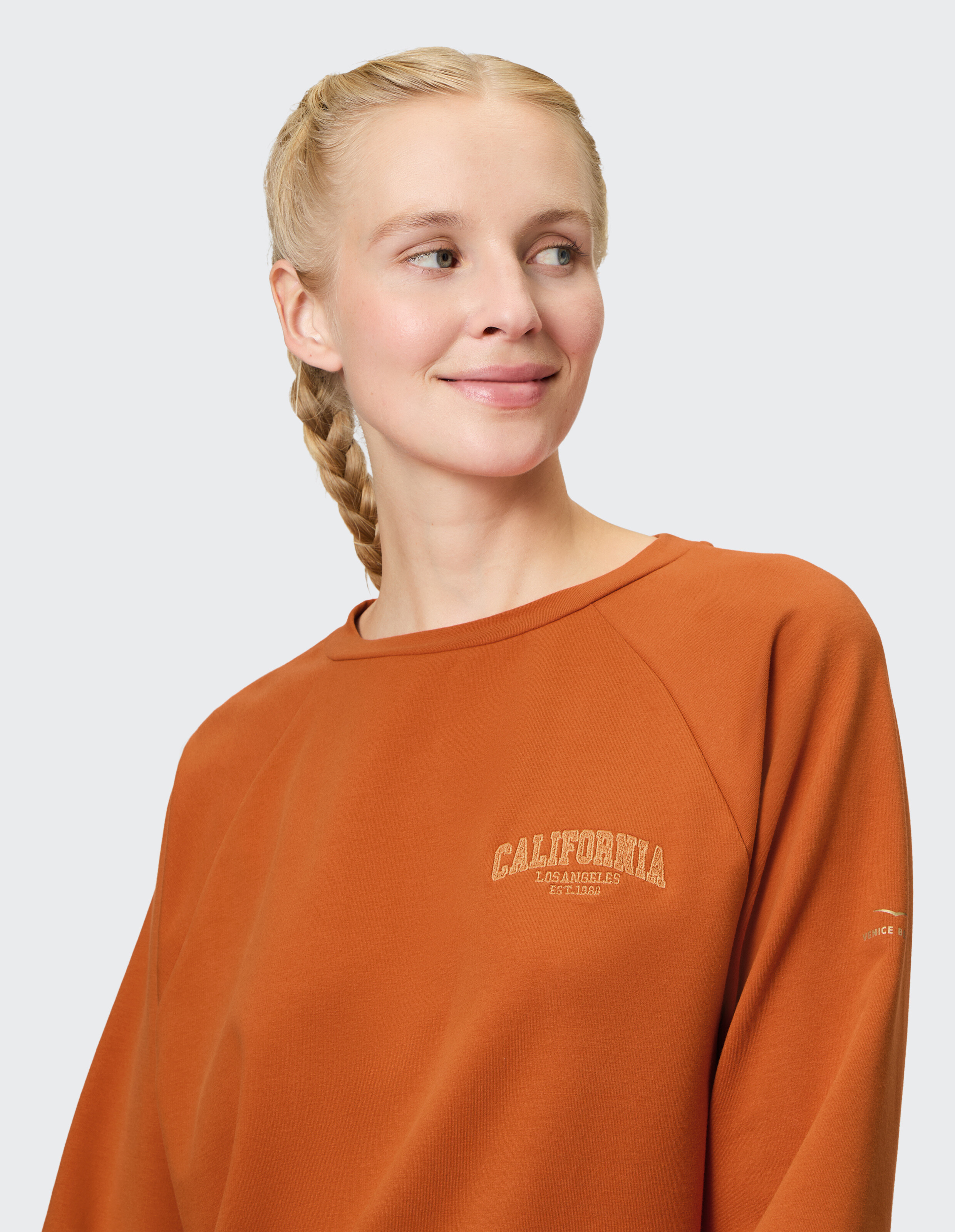 Frau trägt ein gemütliches rostfarbenes California-Sweatshirt für lässige Loungewear.
