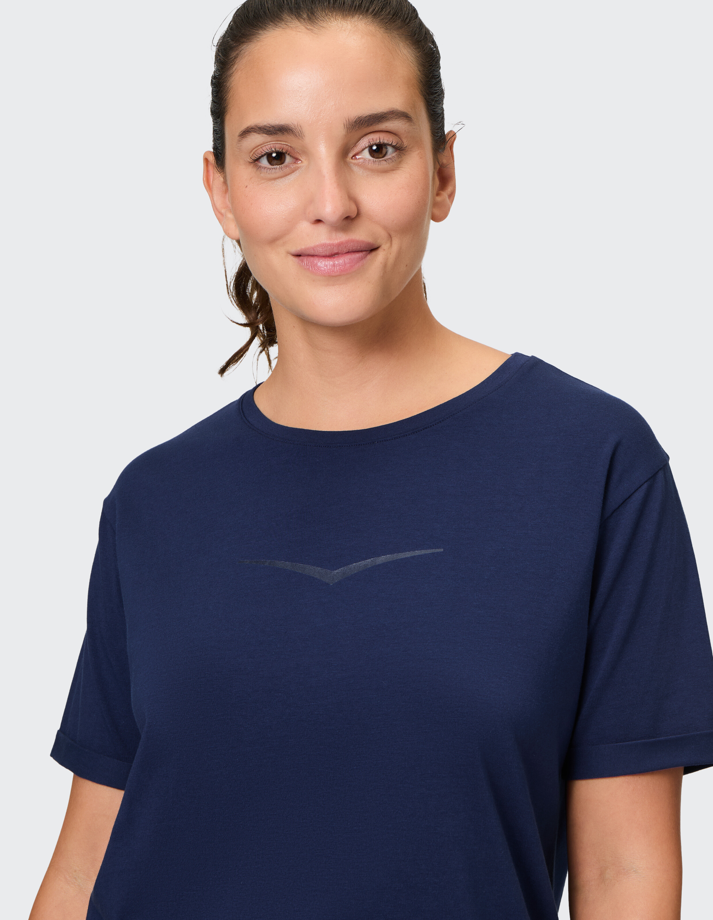 Frau trägt ein marineblaues, lässiges Baumwoll-T-Shirt mit dezentem Logo-Detail.