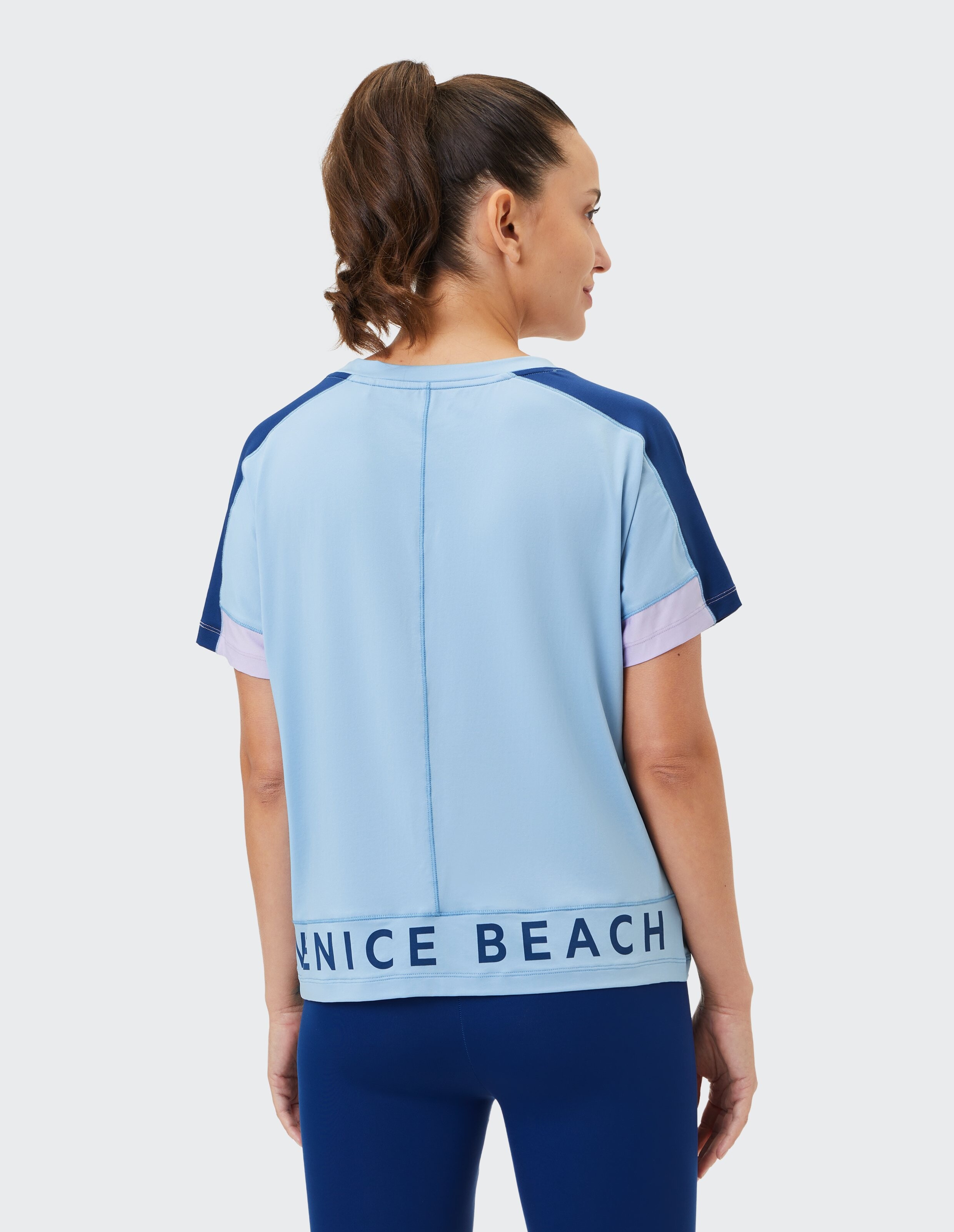 Frau trägt ein hellblaues und marineblaues, lässiges Farbblock-T-Shirt mit „Venice Beach“-Schriftzug.