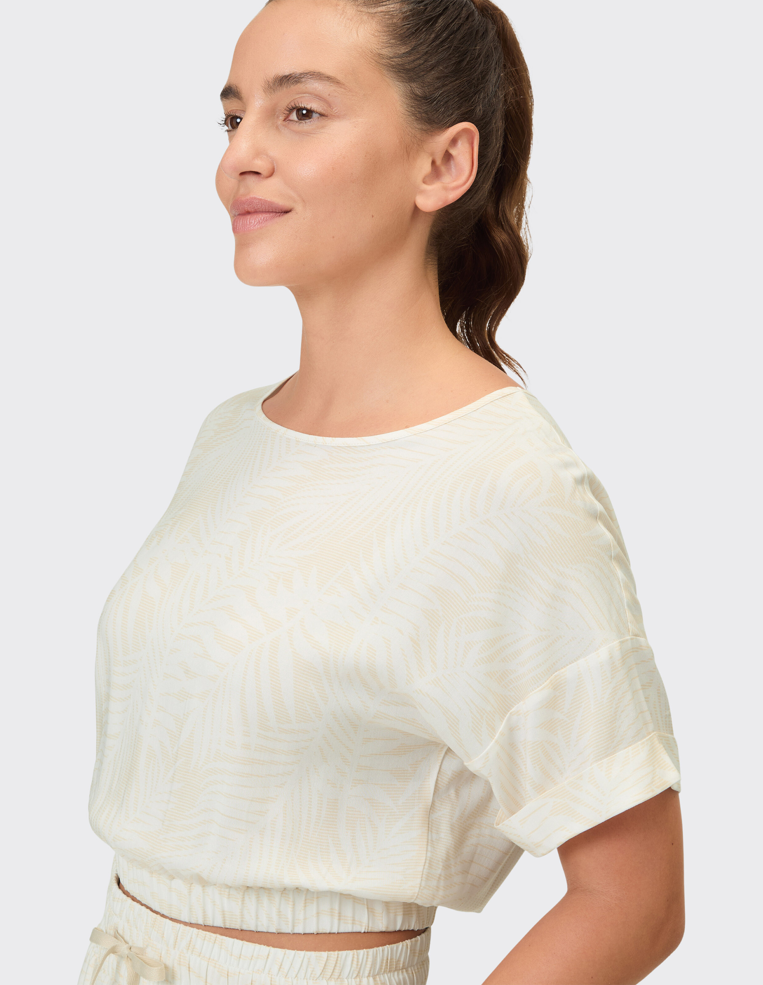 Profilansicht einer Frau in einem leichten, gemusterten Freizeitoberteil mit kurzen Ärmeln.